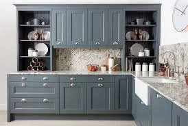 Blue kitchen cabinets with open shelves displaying dishes and glasses, granite countertop, and a white towel hanging from a cabinet handle.