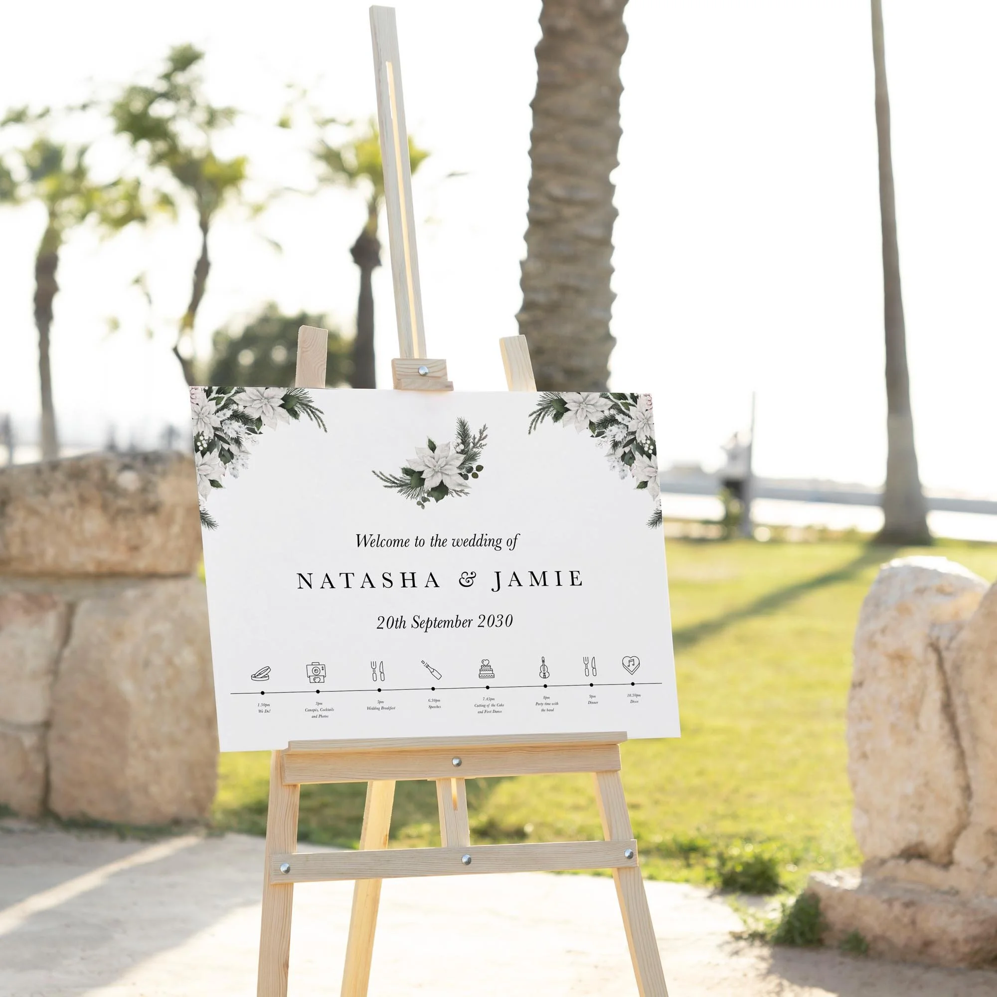 White Poinsettia Winter wedding welcome sign displayed outdoors at a wedding venue on an easel