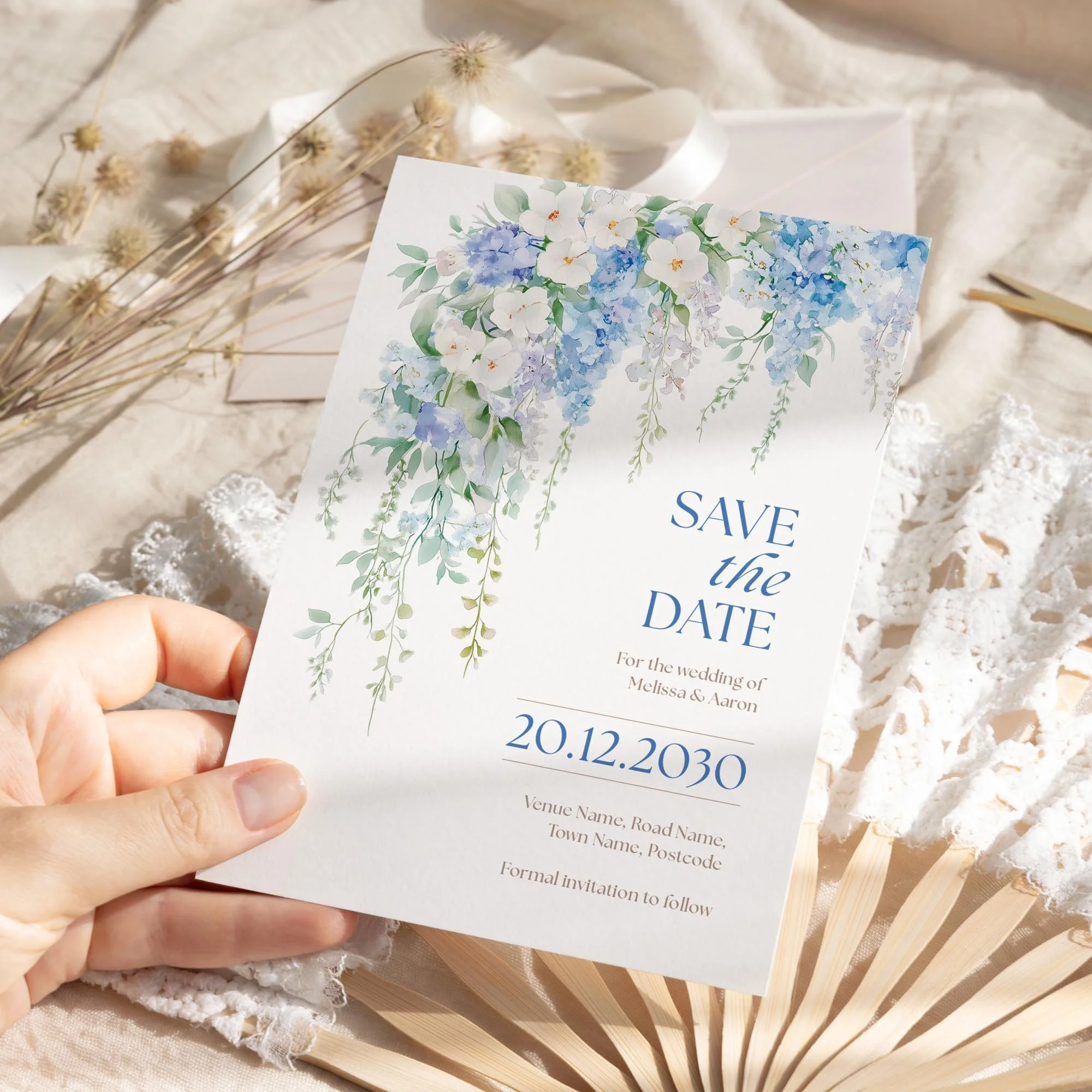 Person holding the Serenity Save the Date with cascading wisteria-style blue flowers.