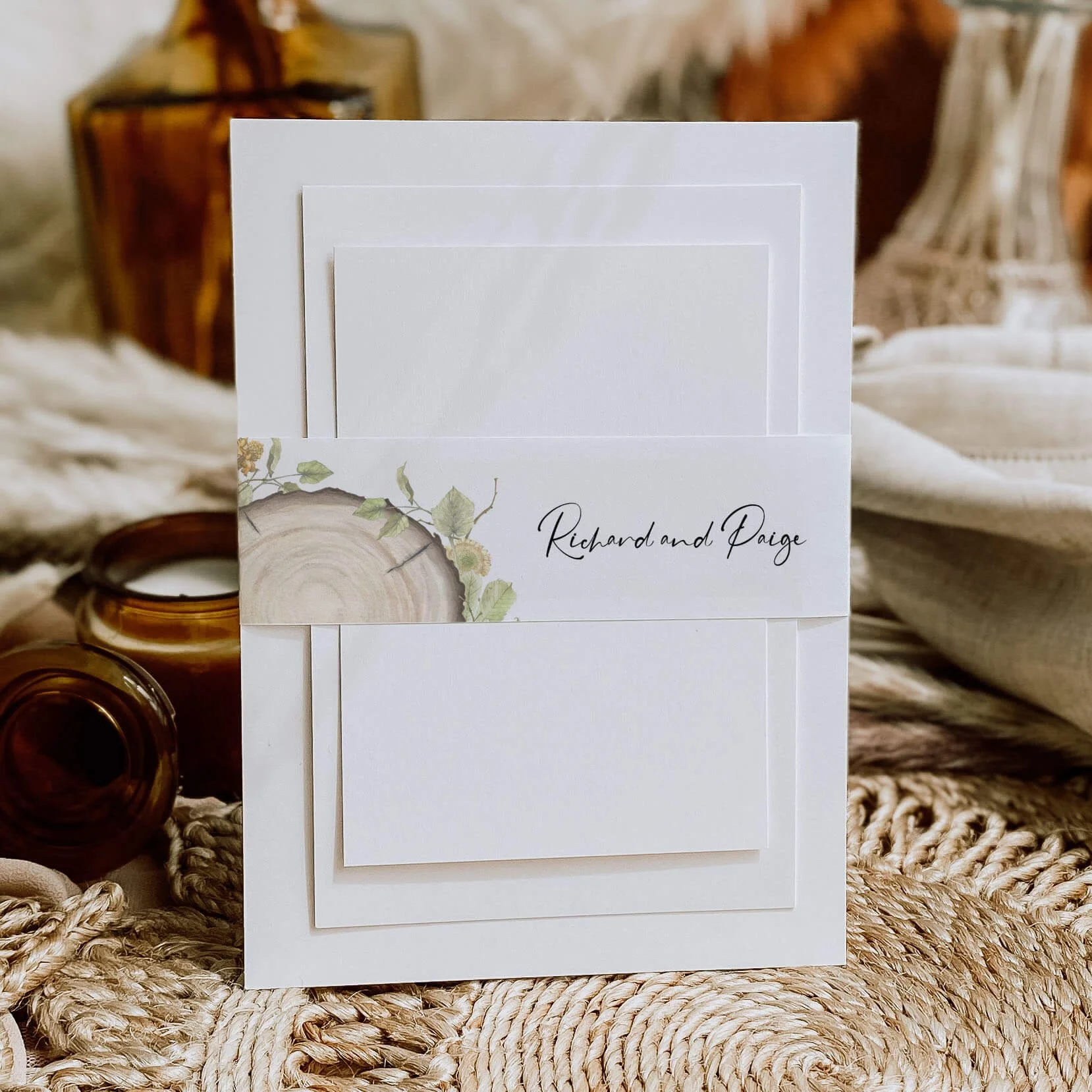 Wood Slice personalised wedding belly bands with watercolour wood cross-section and green botanical leaf illustration and script names wrapped around wedding invitations