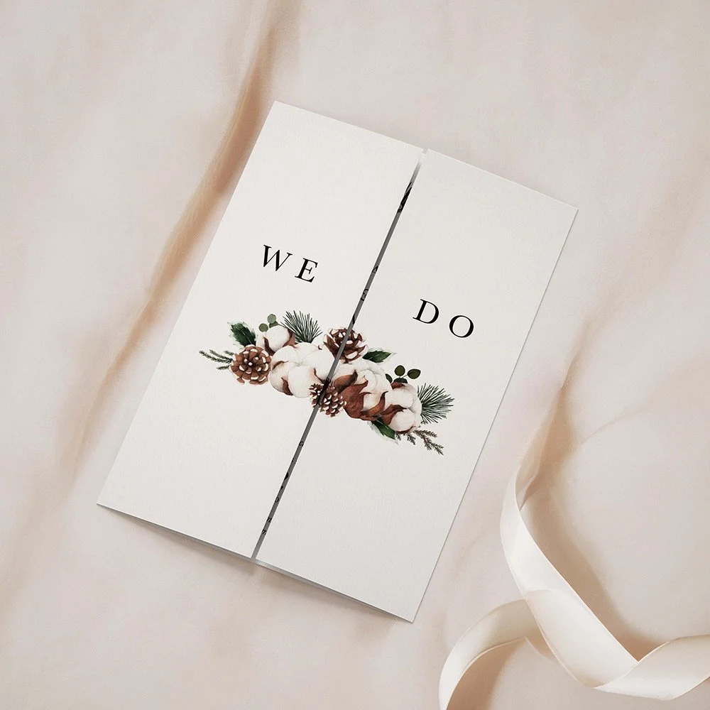 Woodland Collection gatefold wedding invitation closed, featuring pine cones, pine leaves, subtle snow accents, and rustic typography.