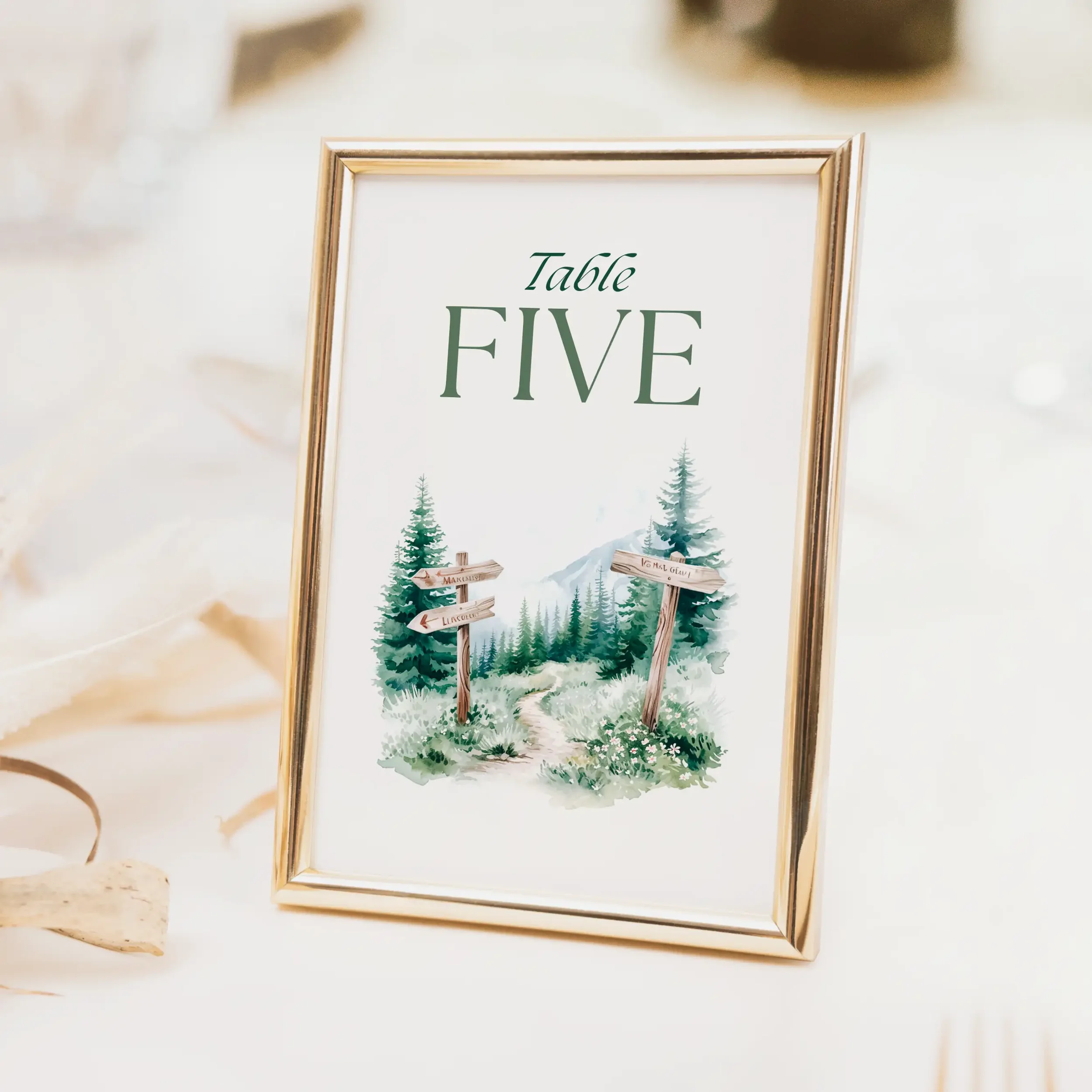 Adventure wedding table number with mountain and forest landscape illustration and mixed script and serif typography, printed on luxury off-white card