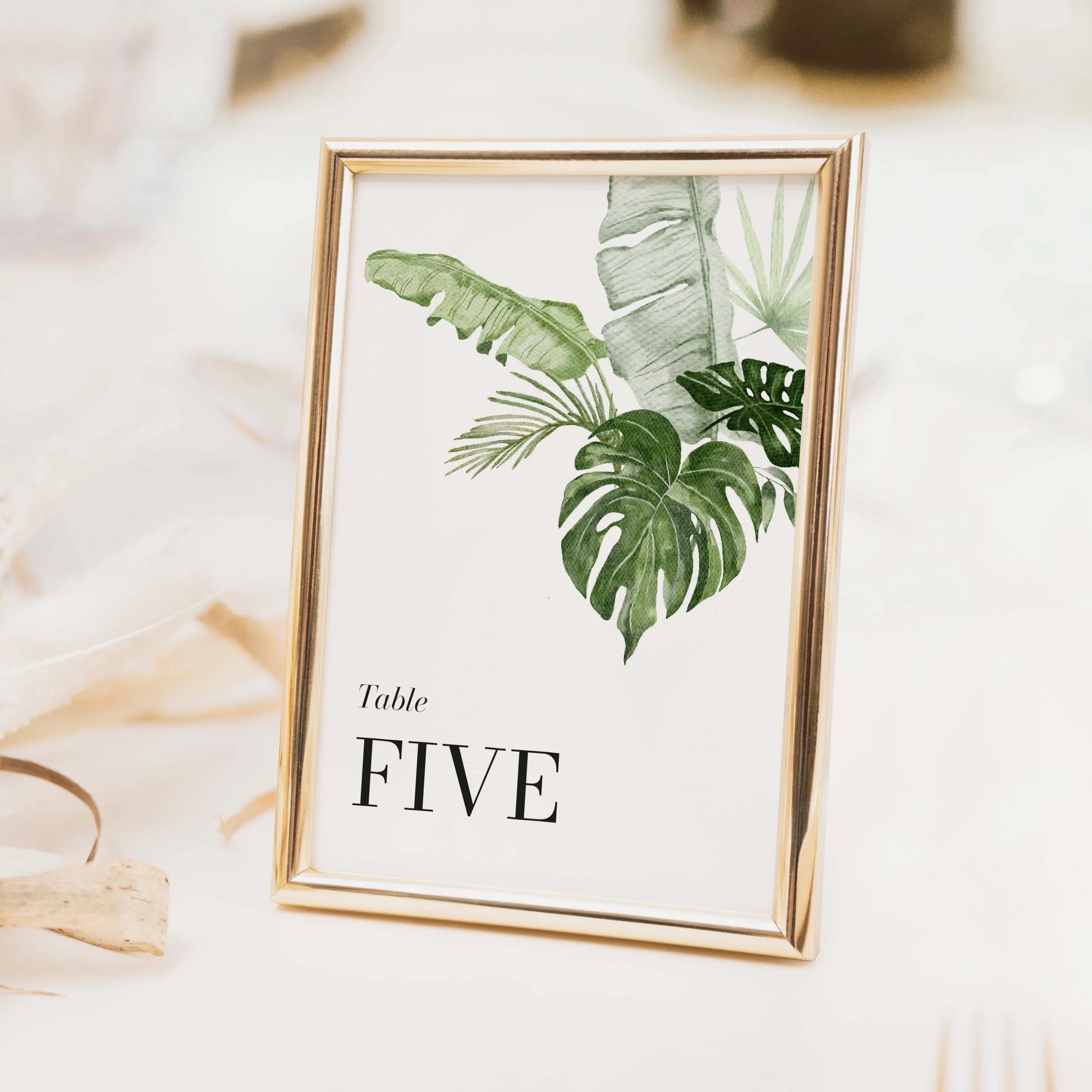 Tropical wedding table number with bold monstera and palm leaf botanical illustration for destination and tropical themed weddings on luxury off-white card