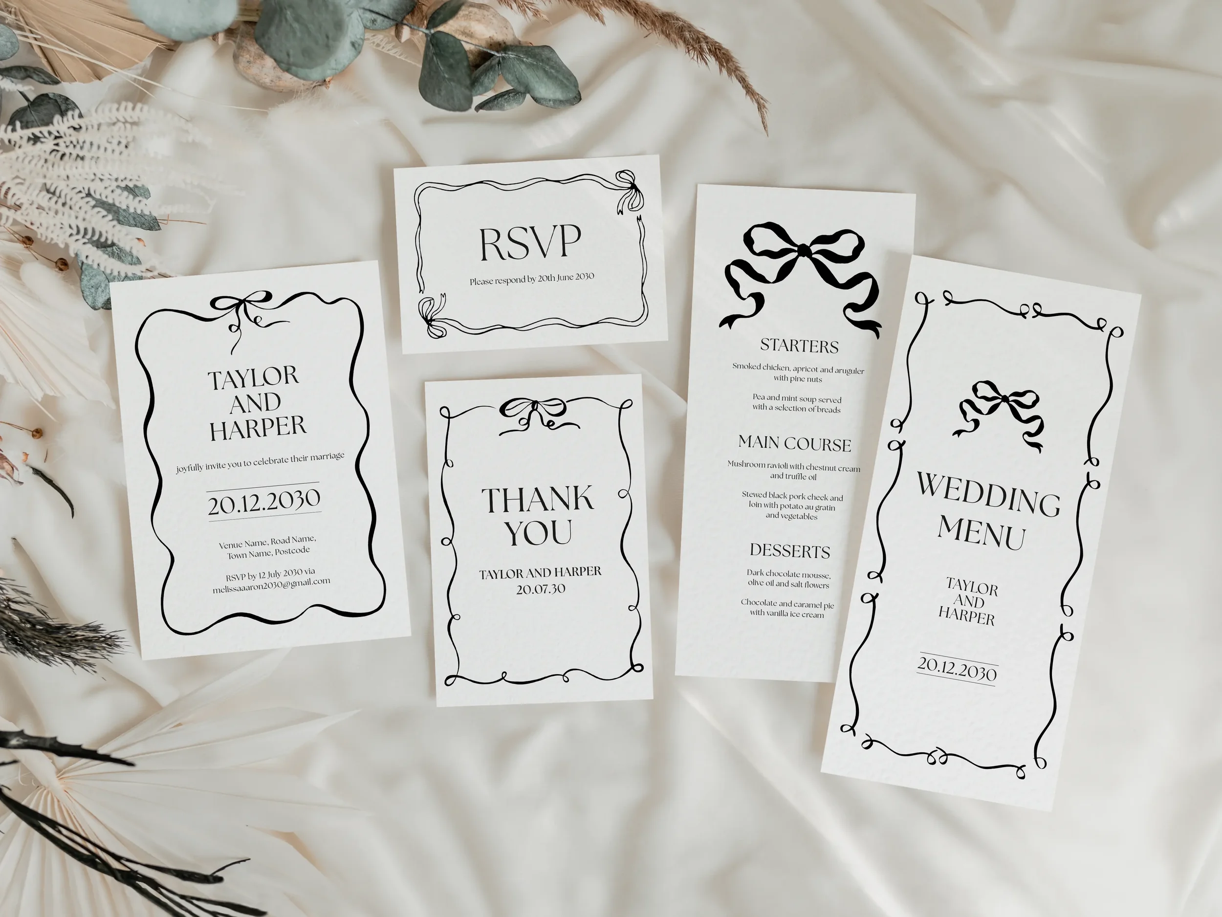 Complete black and white bow wedding stationery suite including invitation, RSVP card, thank you card, and two wedding menu sizes, flat lay styled on white linen