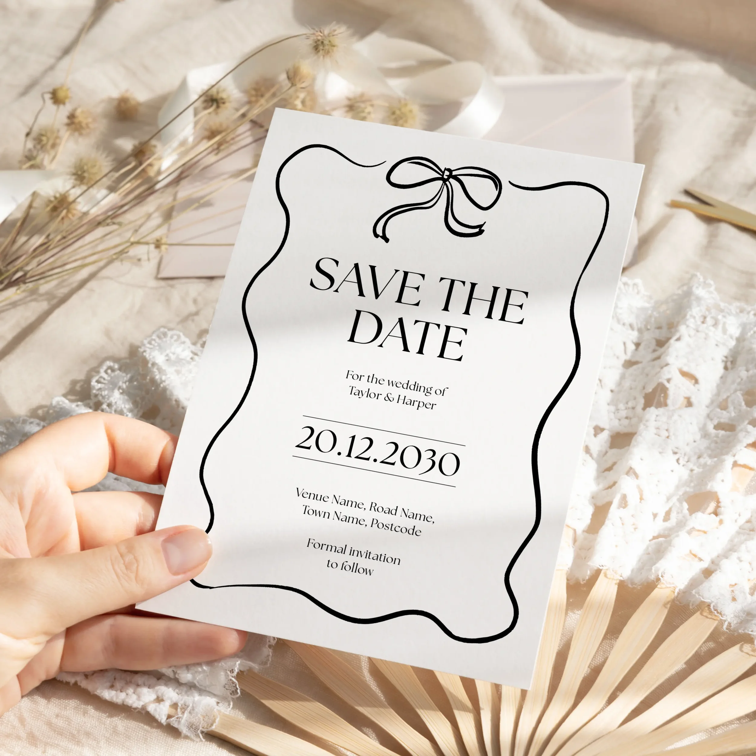 Person holding Black Tie Save the Date wedding card with monochrome design.