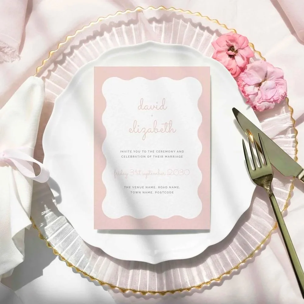Wedding invitation in blush pink, featuring a modern wavy border with gold cutlery to the side.