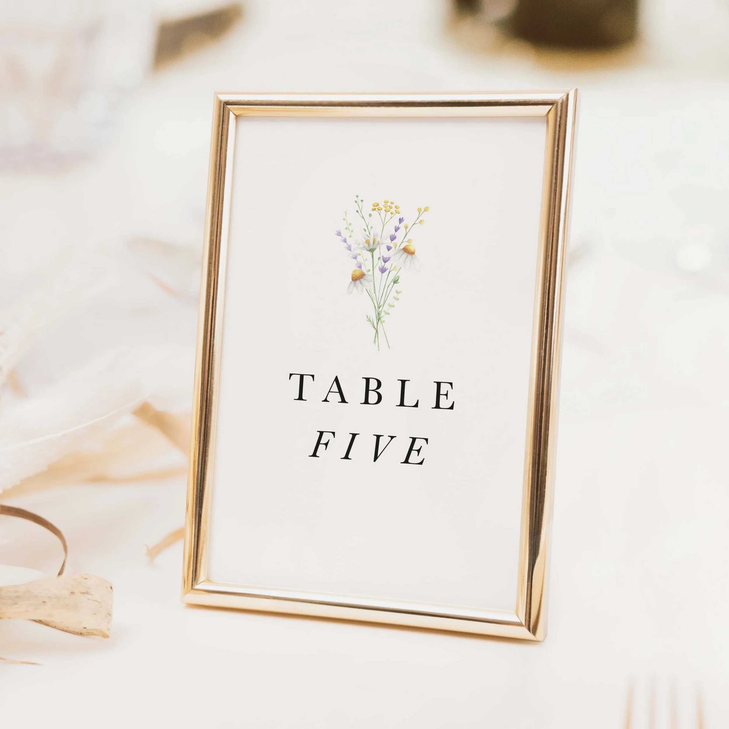 Daisy wedding table number with delicate botanical daisy illustration and elegant spaced serif typography on luxury off-white card
