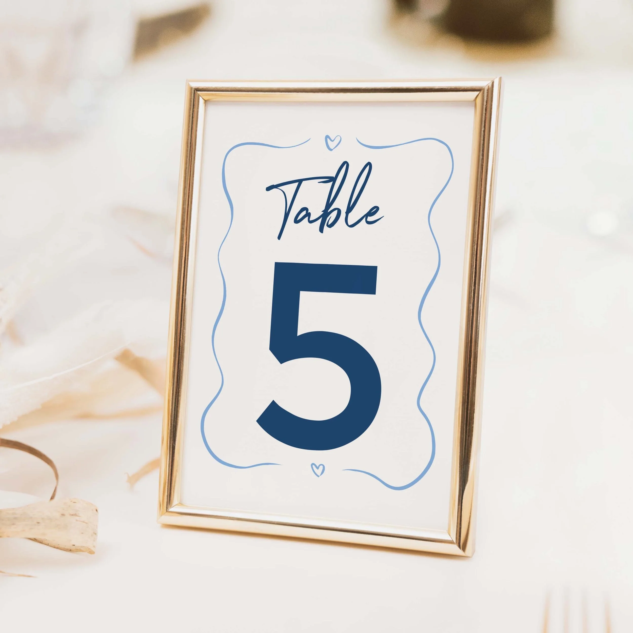Navy blue wavy border wedding table number with large bold numeral and script lettering in modern contemporary style on luxury off-white card