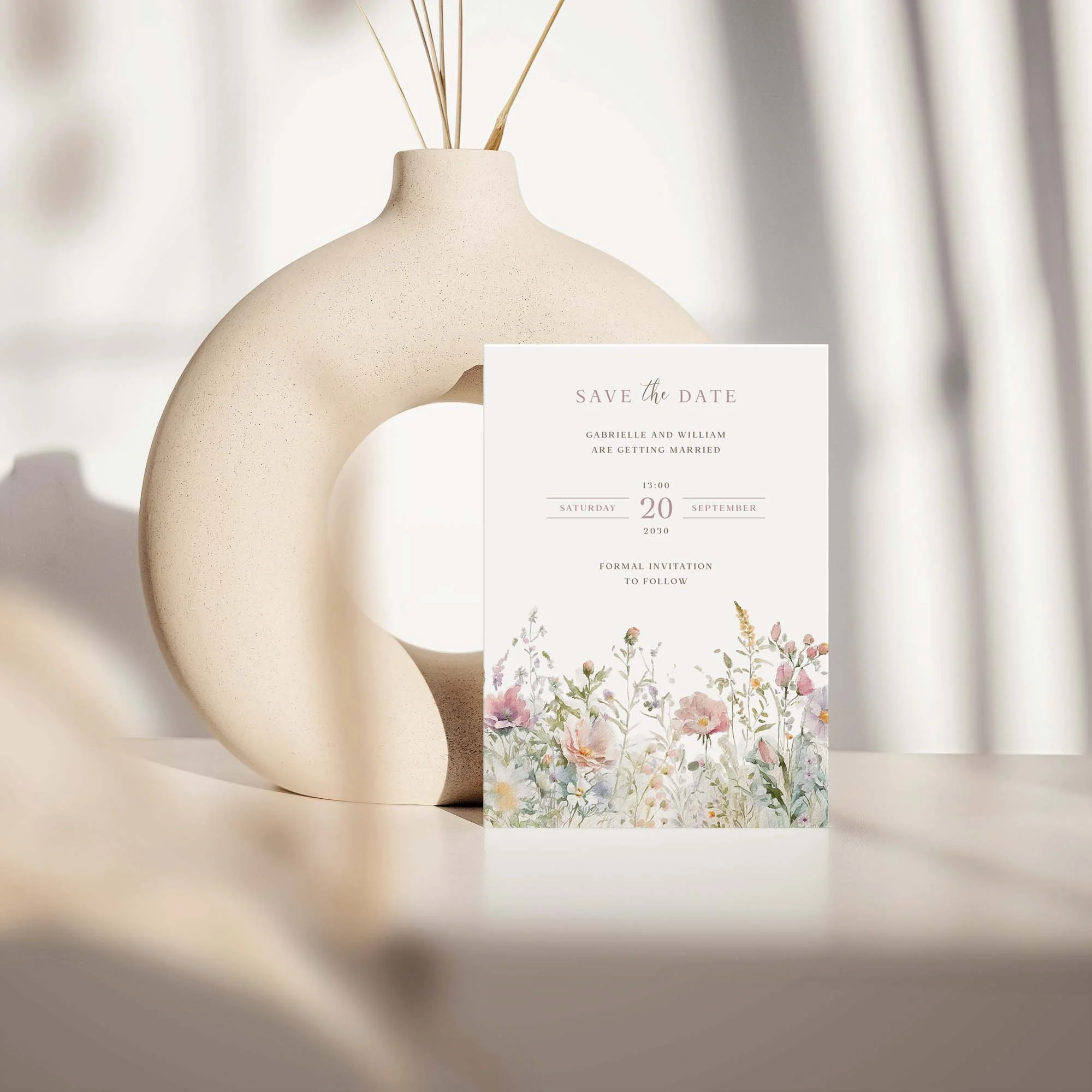 Field Powder save the date card with dusty pink pastel wildflowers design displayed against a cream ceramic vase on a neutral background