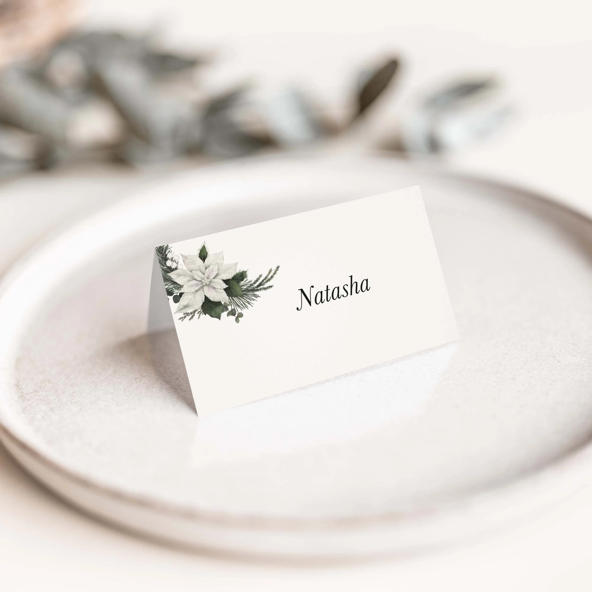 Winter Frost wedding place card with poinsettia winter botanical illustration and flowing guest name on luxury off-white card