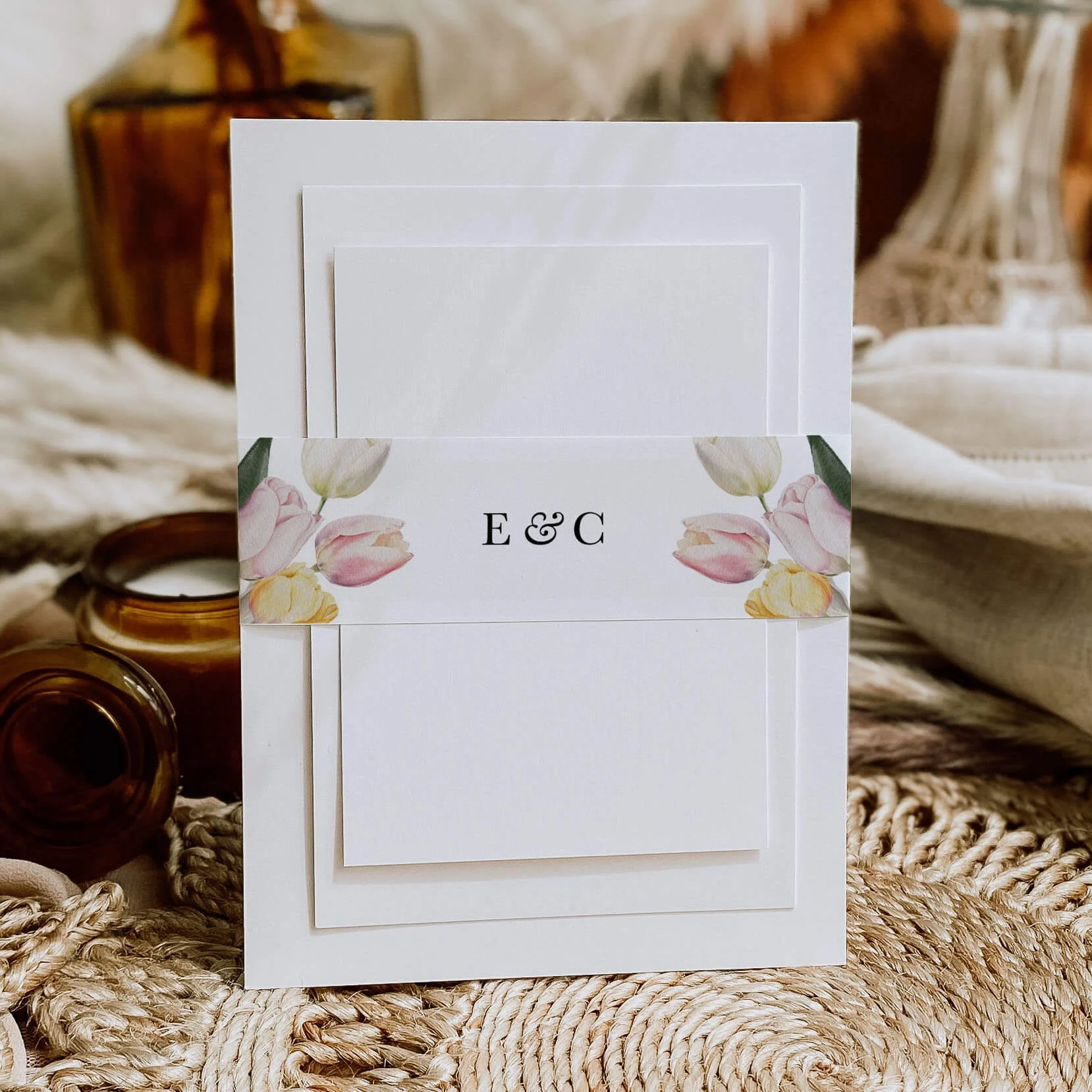 Tulip personalised wedding belly bands with soft pink and yellow watercolour tulip illustration and serif initials wrapped around wedding invitations