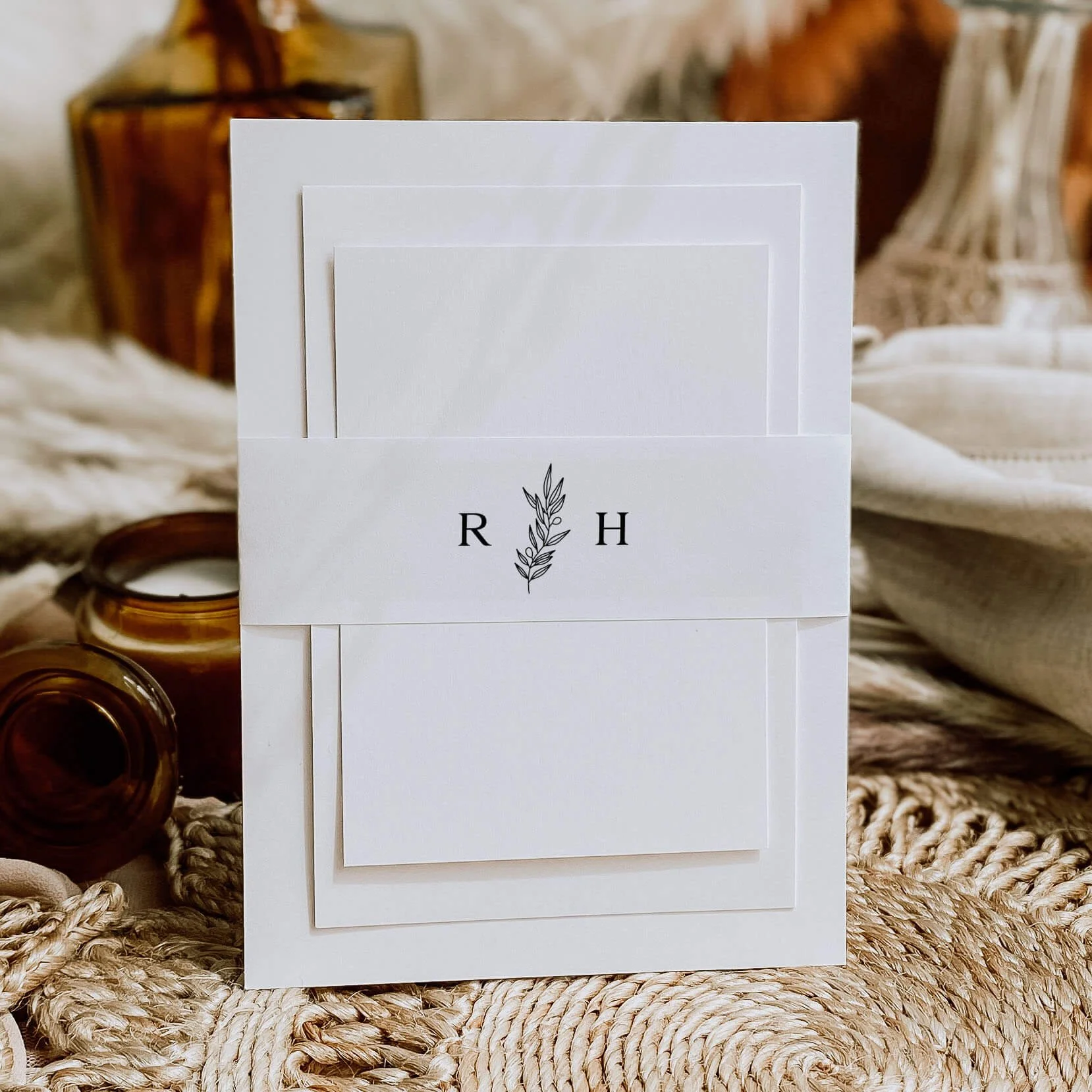 Heritage personalised wedding belly bands with monogram initials and botanical line art sprig illustration wrapped around wedding invitations