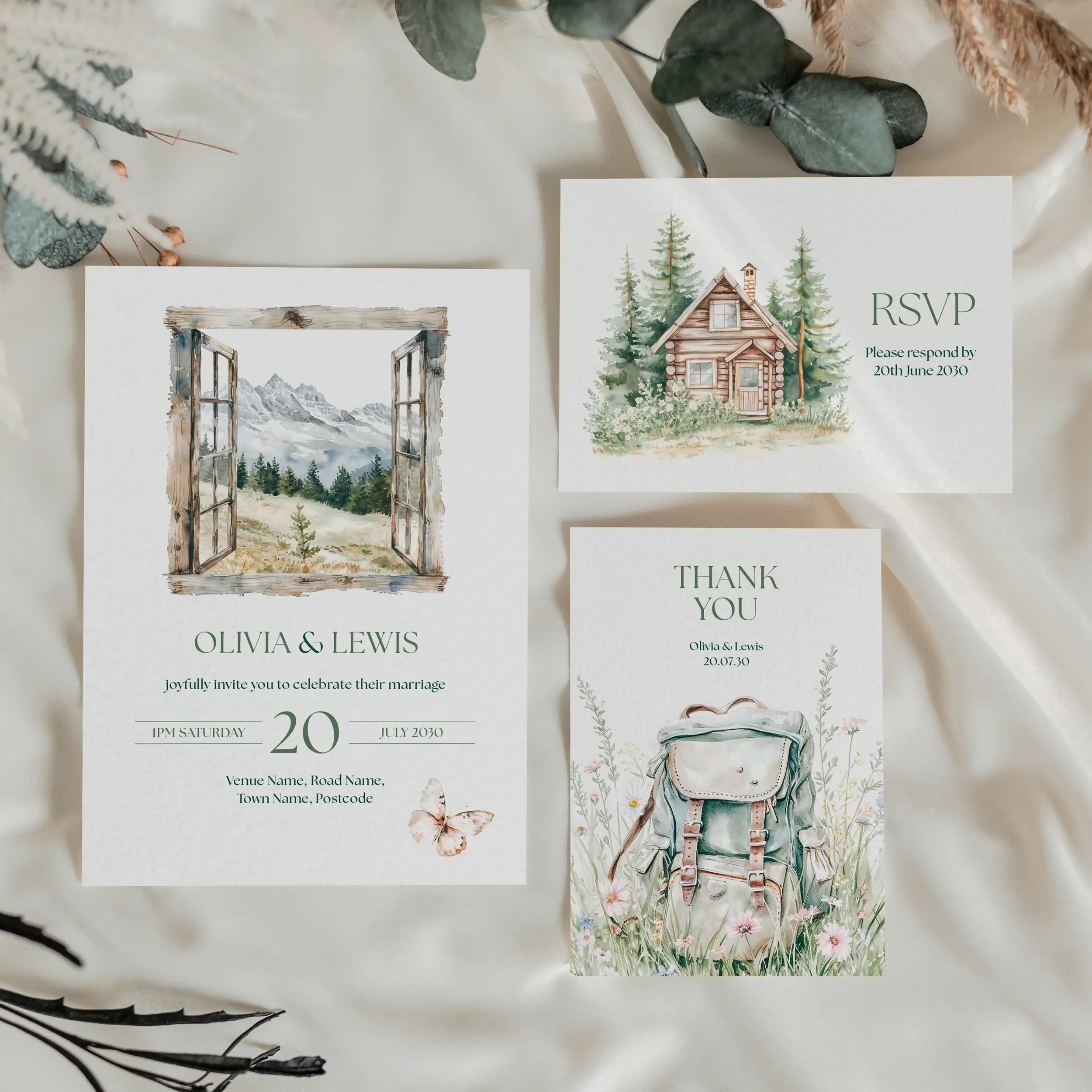 Adventure wedding stationery suite flat lay showing invitations, RSVP cards and coordinating pieces with watercolour mountain and forest illustrations