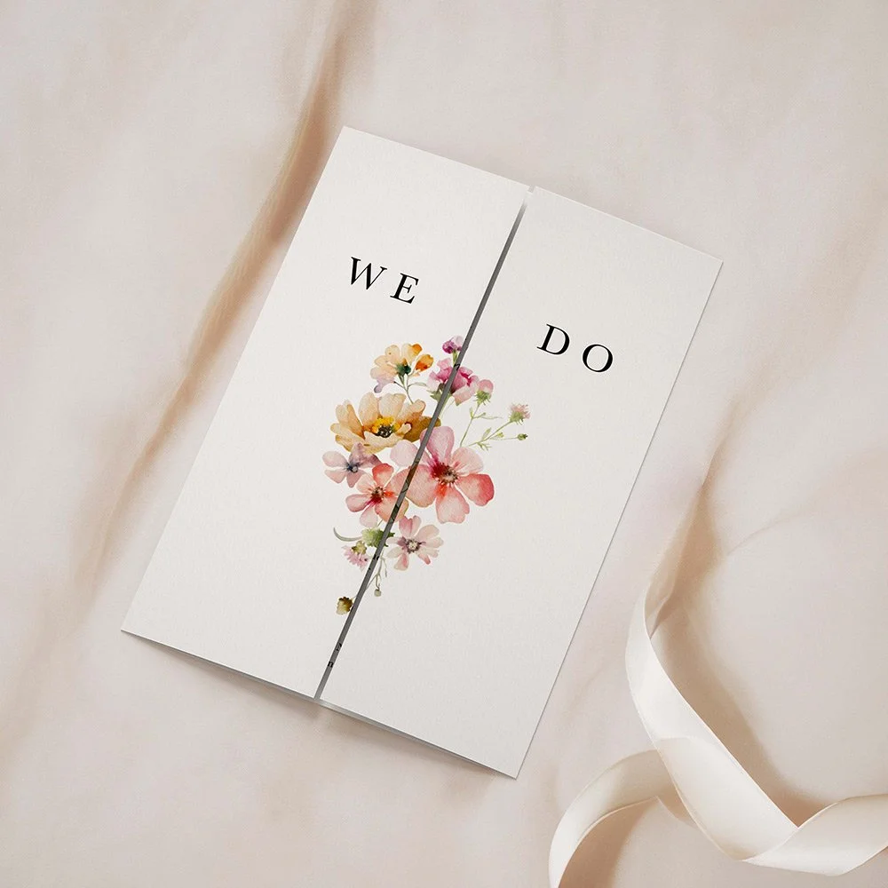 Bloom Collection gatefold wedding invitation closed, featuring soft pastel florals in blush, peach, and lilac tones around elegant modern text.