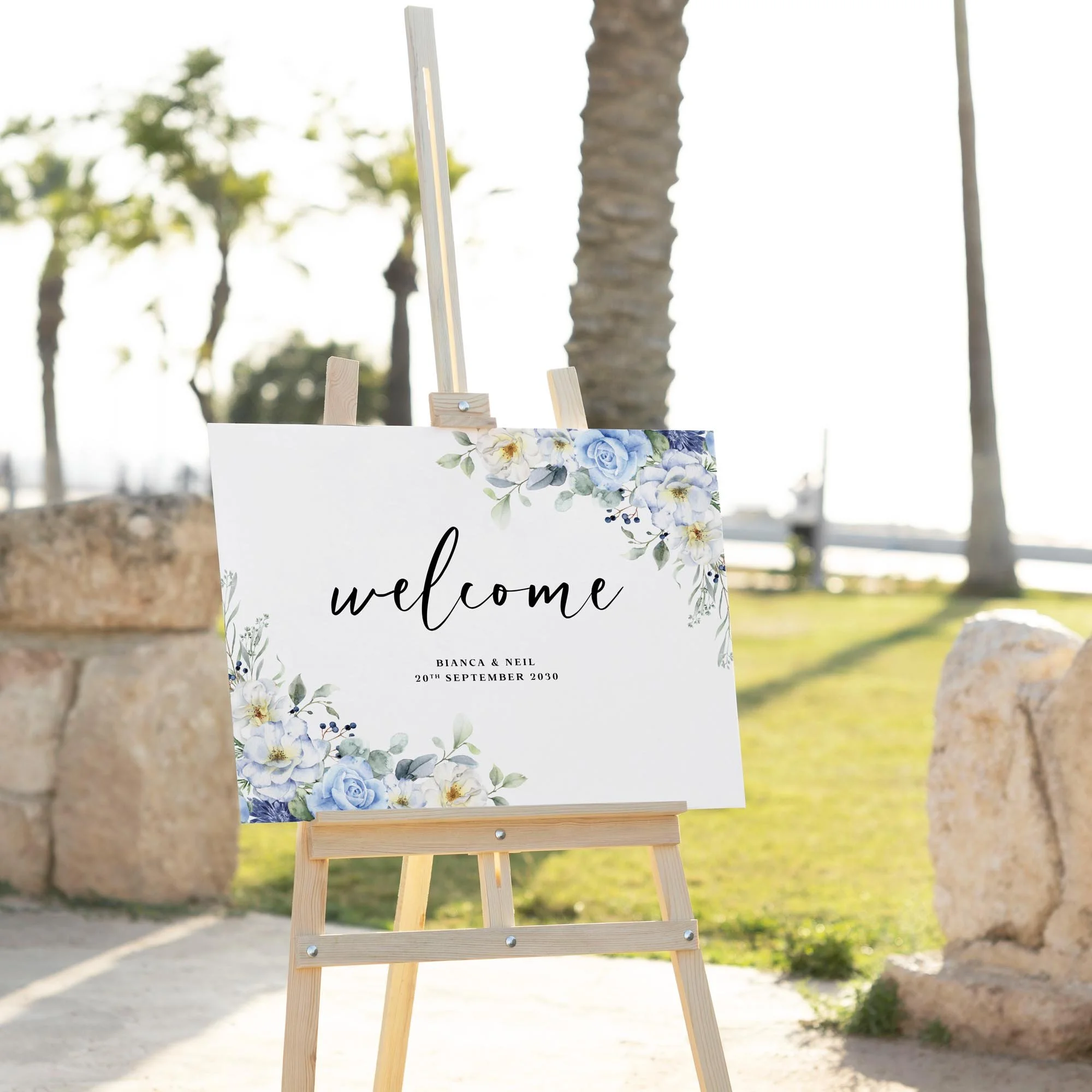 Blue Floral wedding welcome sign displayed outdoors at a wedding venue on an easel