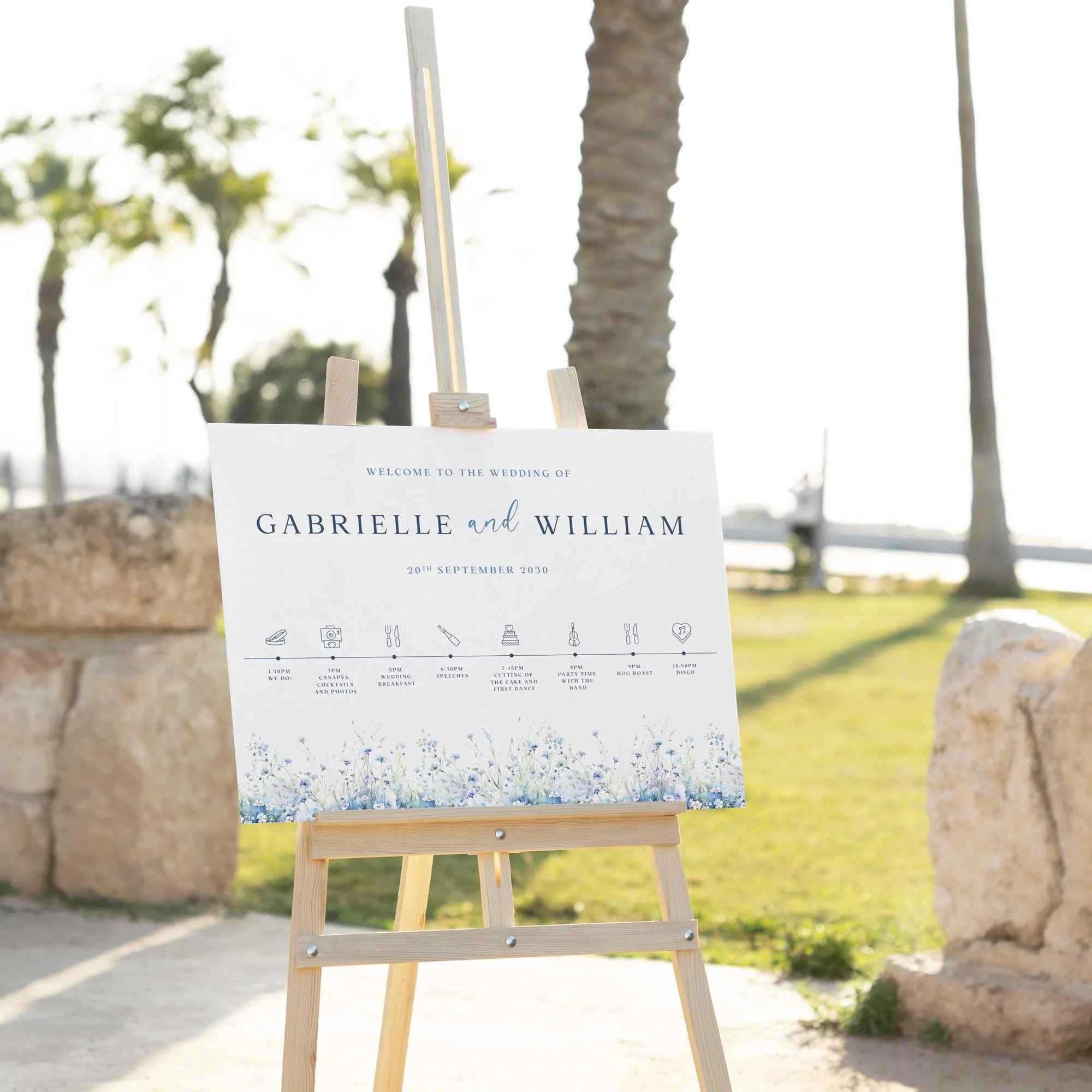 Dusty Blue Field Flowers wedding welcome sign displayed outdoors at a wedding venue on an easel