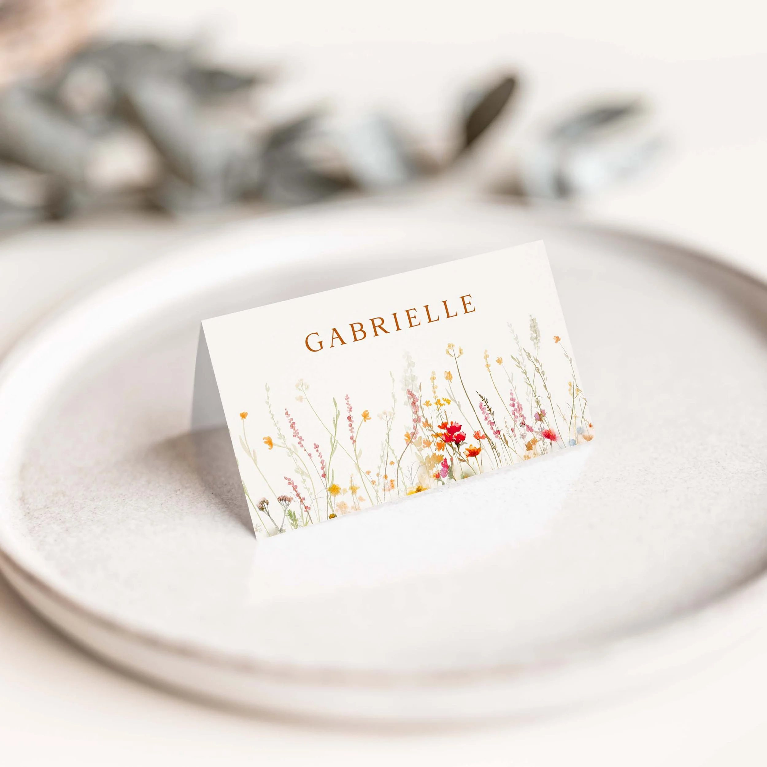 Vermillion wildflower wedding place card with warm floral border along the bottom
