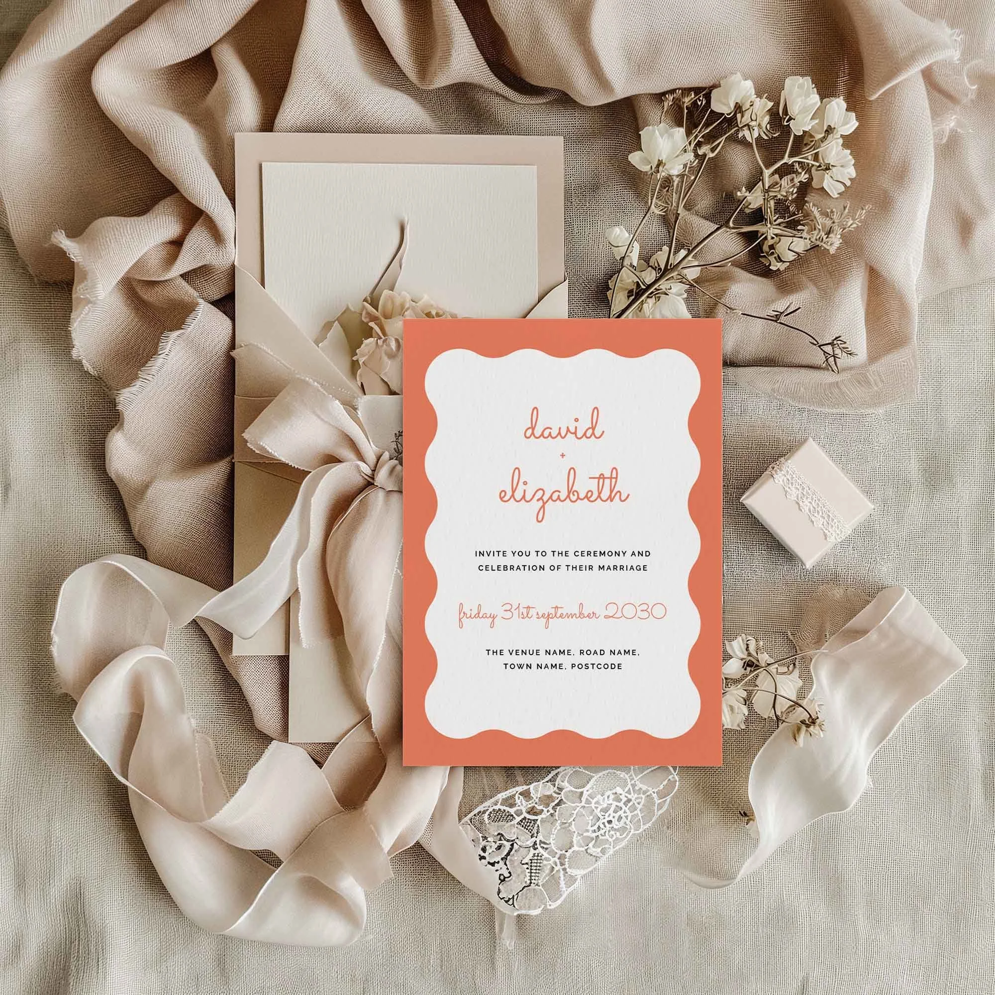 Scallop wedding invitation styled in a flat lay environment with wedding props