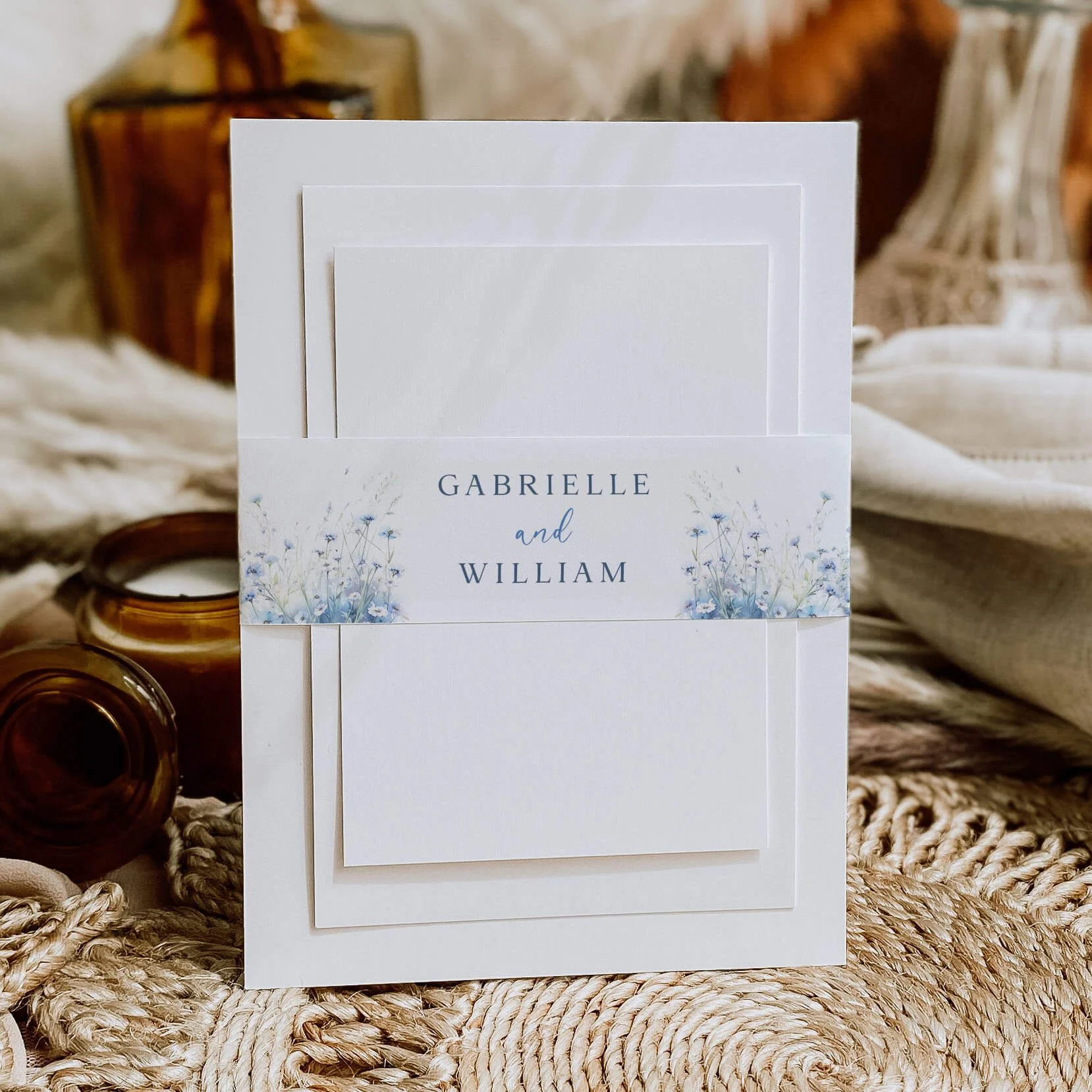 Field Dusty Blue personalised wedding belly bands with blue wildflower meadow illustration and dusty blue names wrapped around wedding invitations