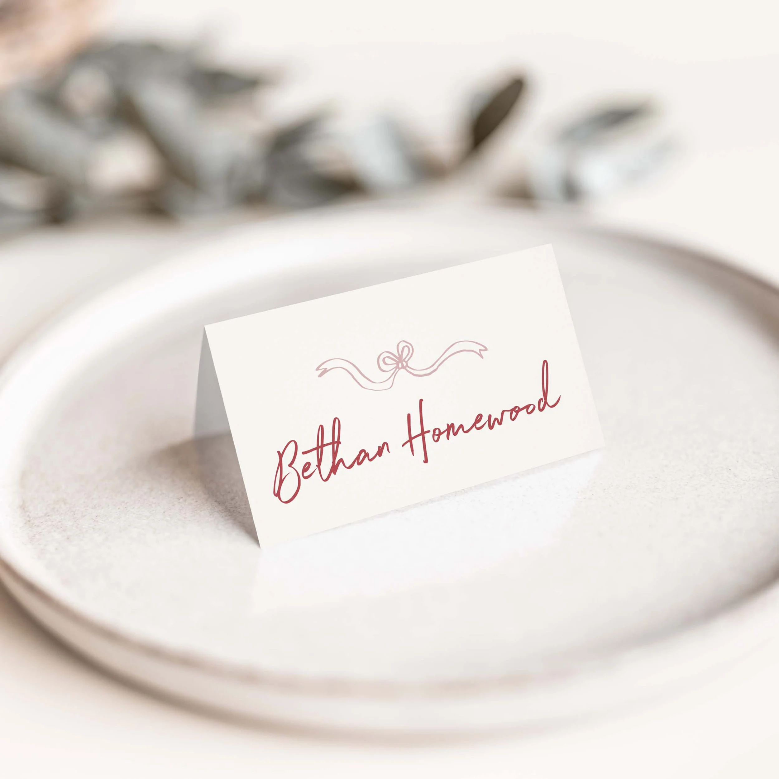 Whimsical Pink wedding place card with pink calligraphy ribbon flourish and script guest name on luxury off-white card