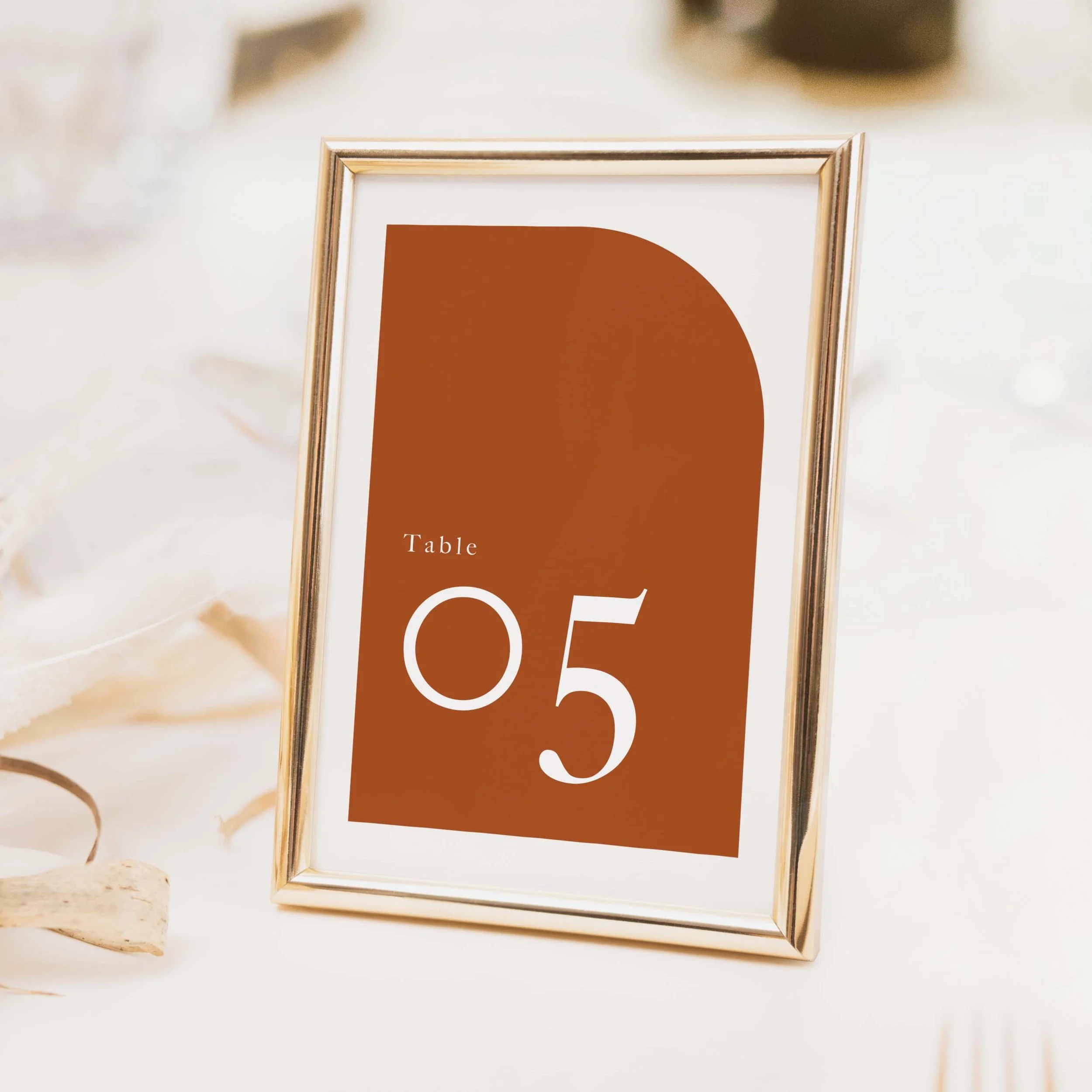 Arch wedding table number with terracotta arch shape and bold modern typography, printed on luxury off-white card