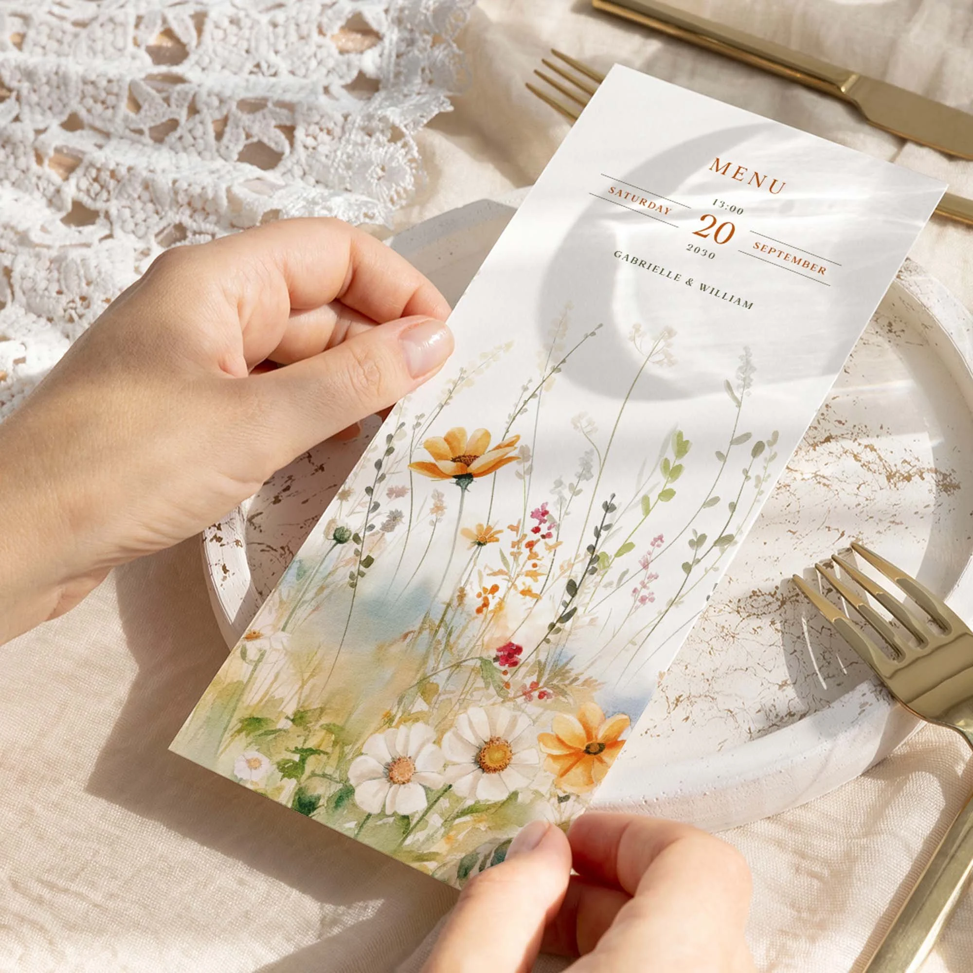 Hand holding a Field Vermilion wedding breakfast menu card with bright orange cosmos and golden daisy wildflower border illustration