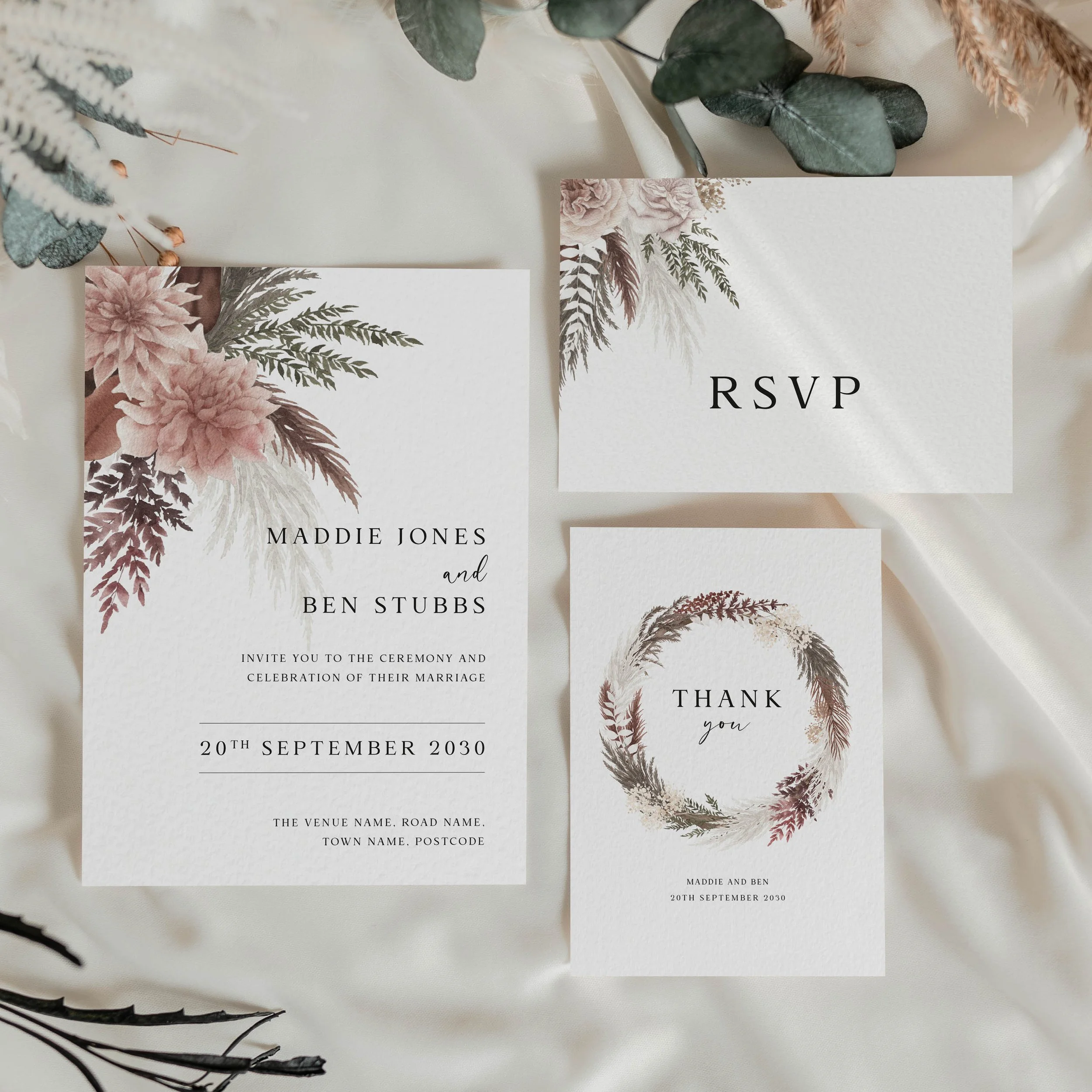 Blush Boho wedding stationery suite flat lay showing invitations, RSVP cards and coordinating pieces with pampas grass, ferns and blush pink dahlia illustration