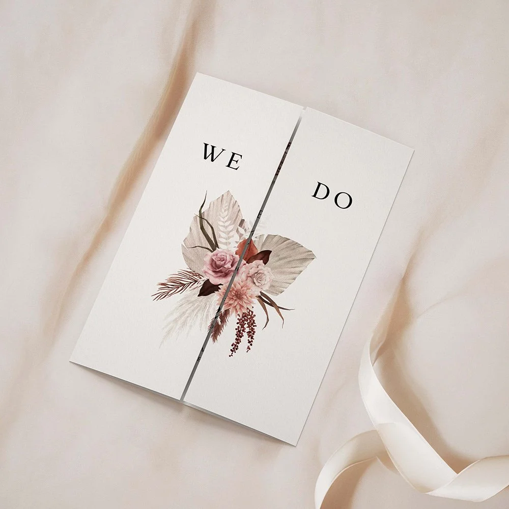 Blush Boho Collection gatefold invitation closed, featuring large dried florals in blush, peach, and brown tones with sage green foliage in the top left corner.