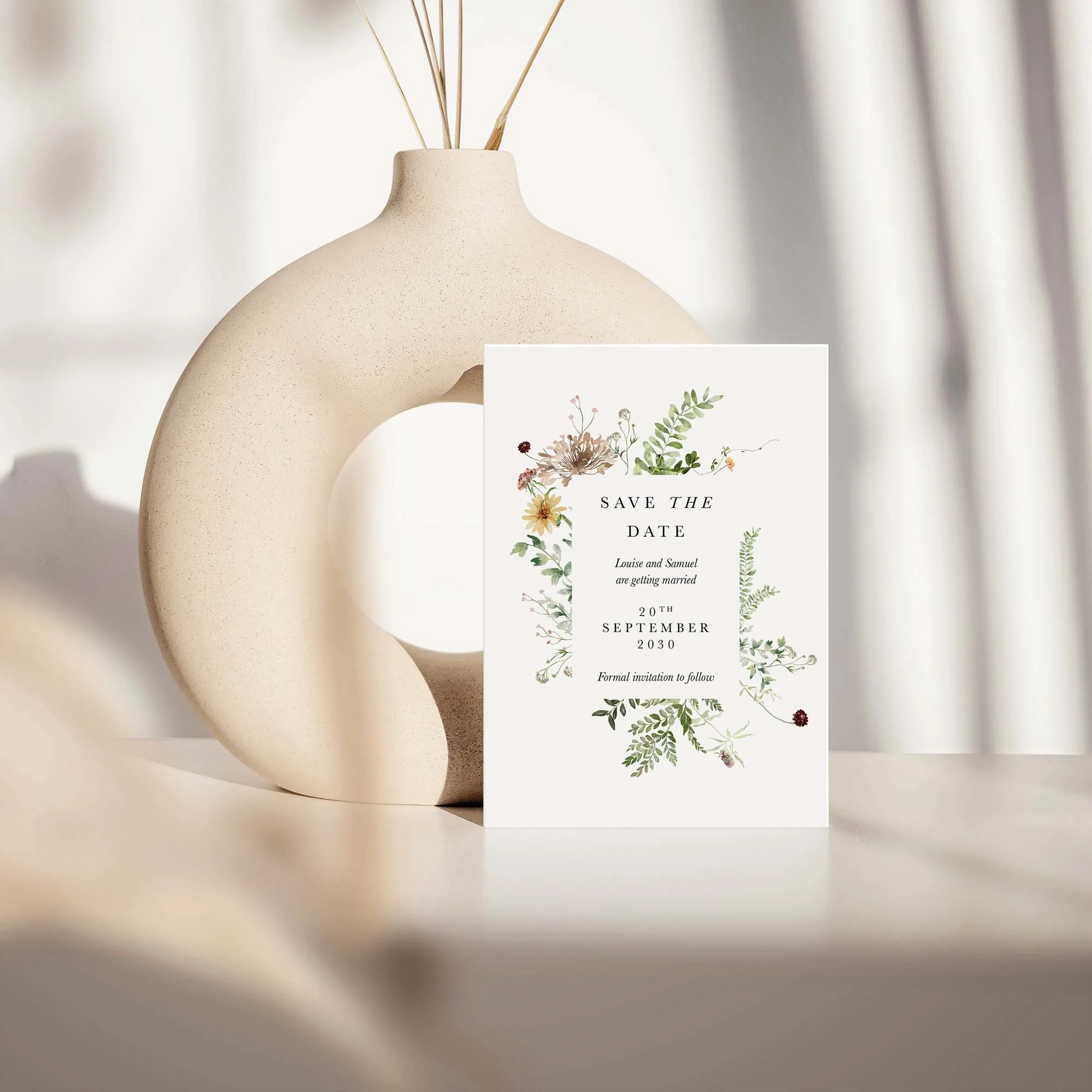 Meadow save the date card with rustic wildflowers design displayed against a cream ceramic vase on a neutral background