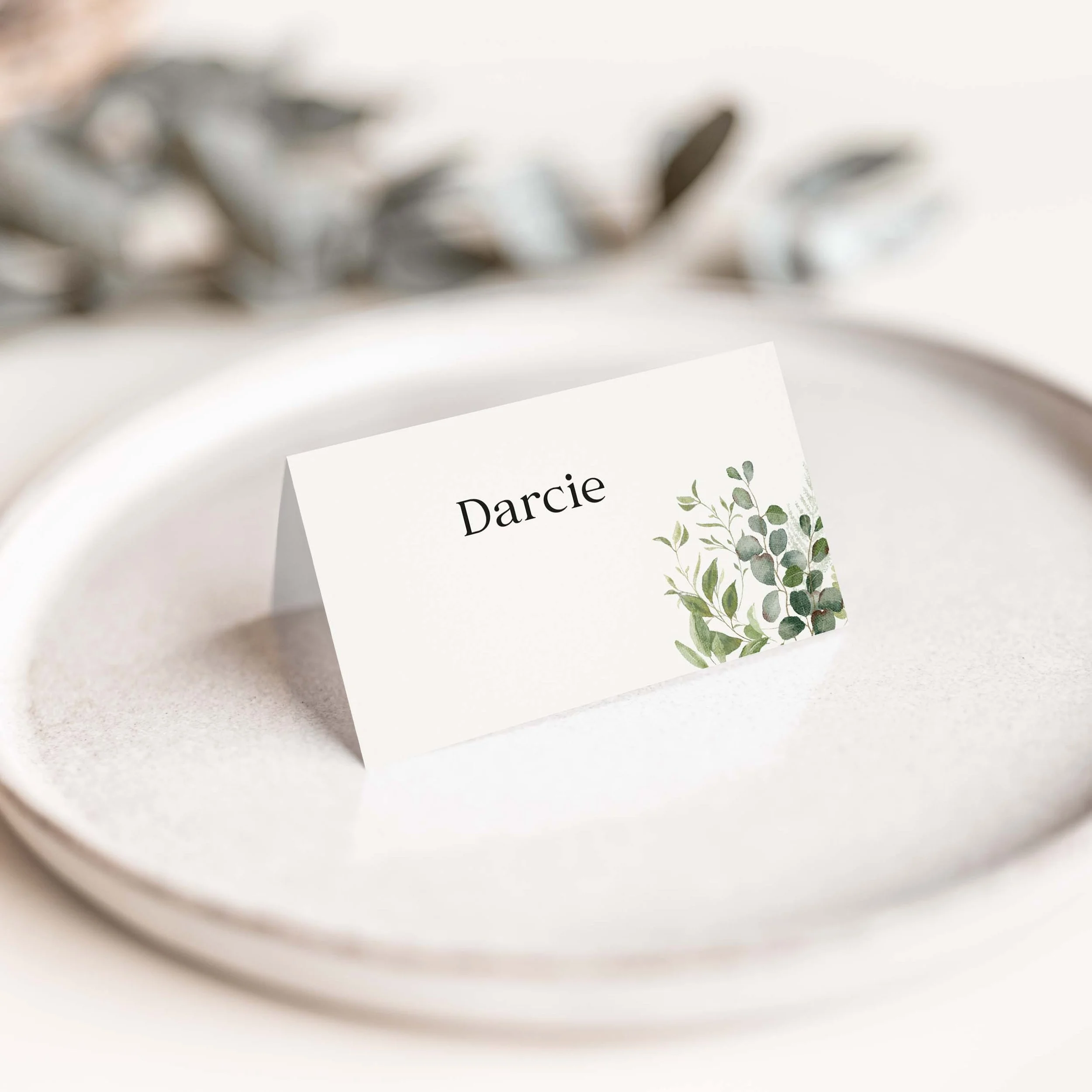 Venue Greenery wedding place card with delicate botanical illustration and clean serif guest name typography on luxury off-white card