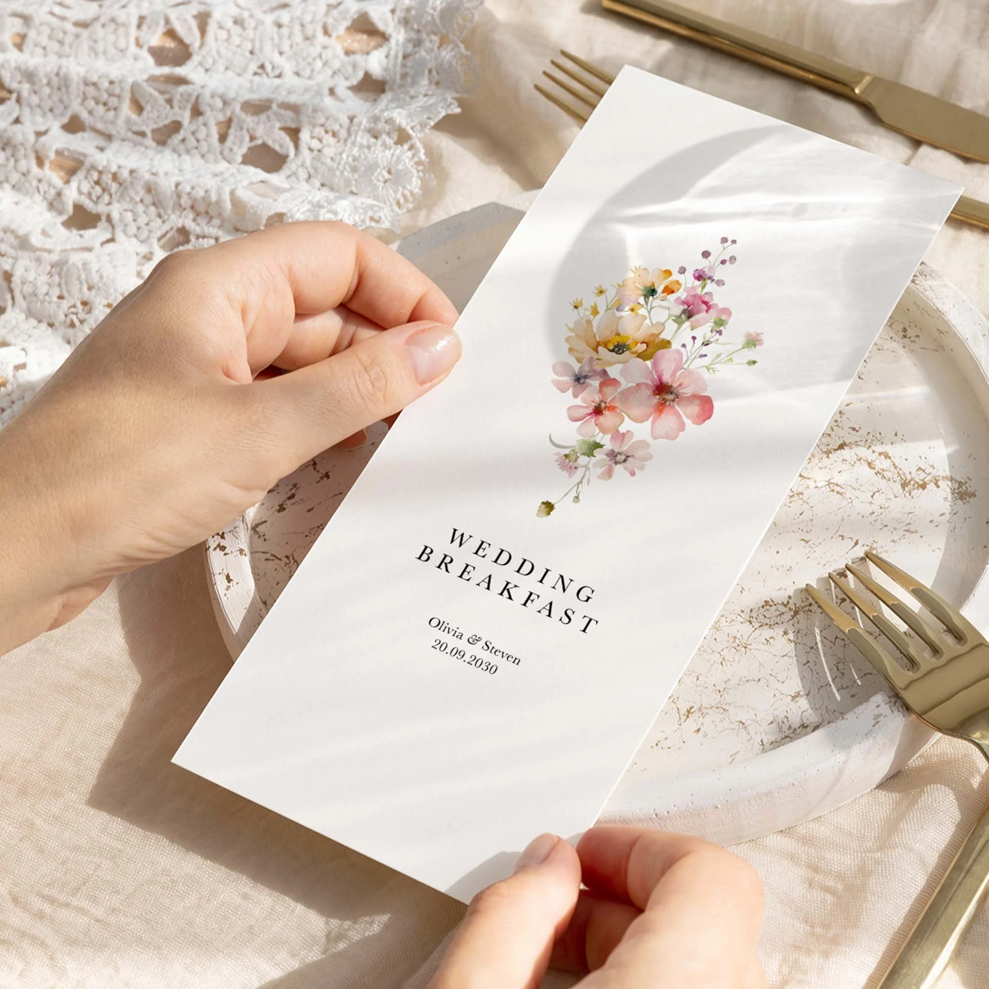 Hand holding a Bloom wedding breakfast menu card with watercolour wildflower design in soft pastel tones