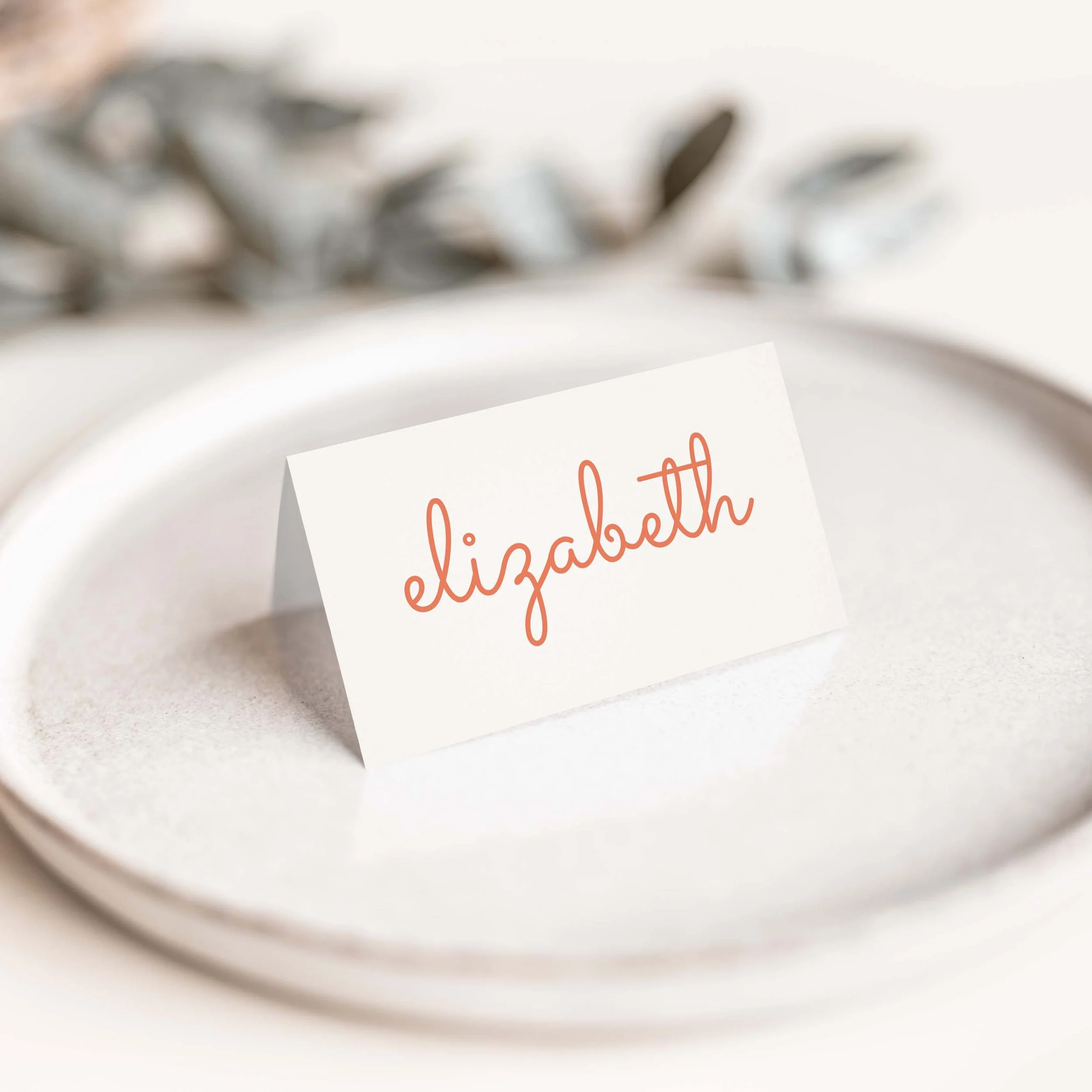 Scallop wedding place card with flowing calligraphy script guest name on luxury off-white card