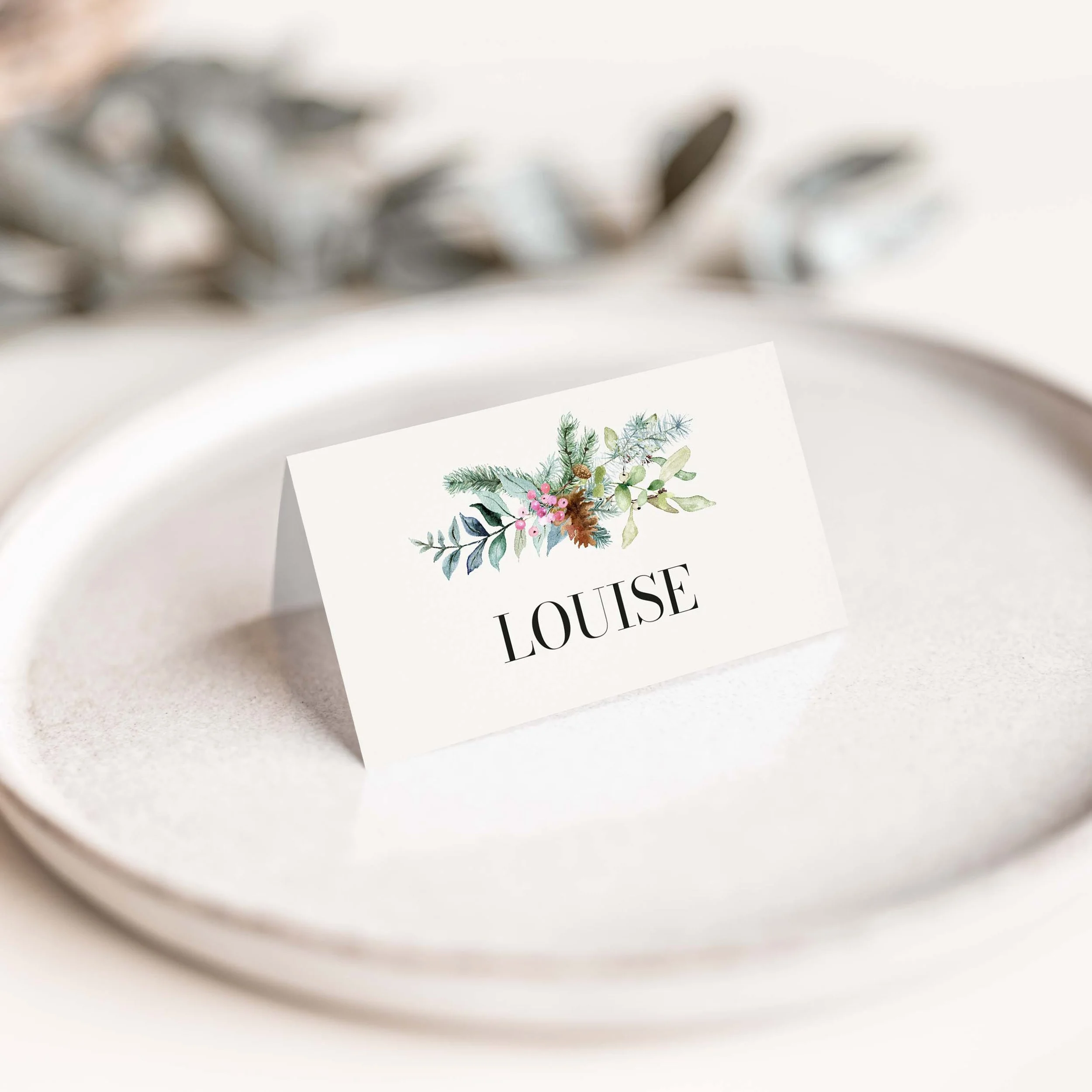 Festive wedding place card with winter greenery and floral detail
