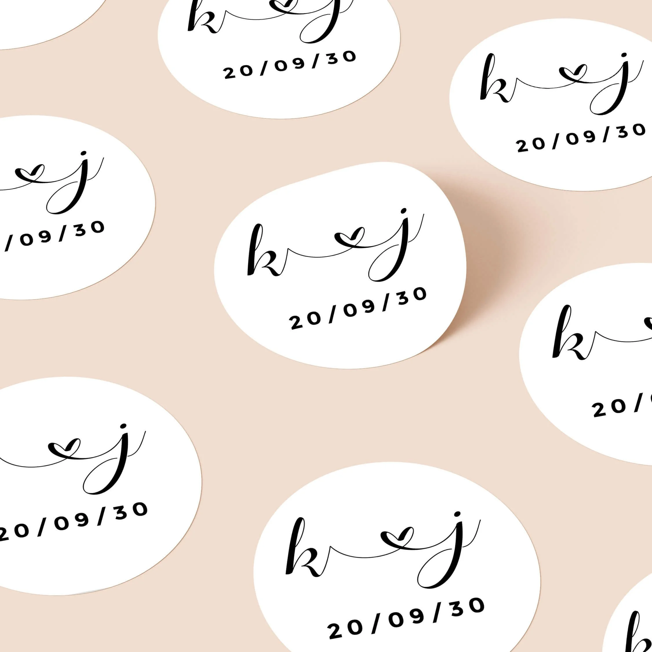 Calligraphy wedding stickers with handwritten initials and heart detail repeated on personalised round seals