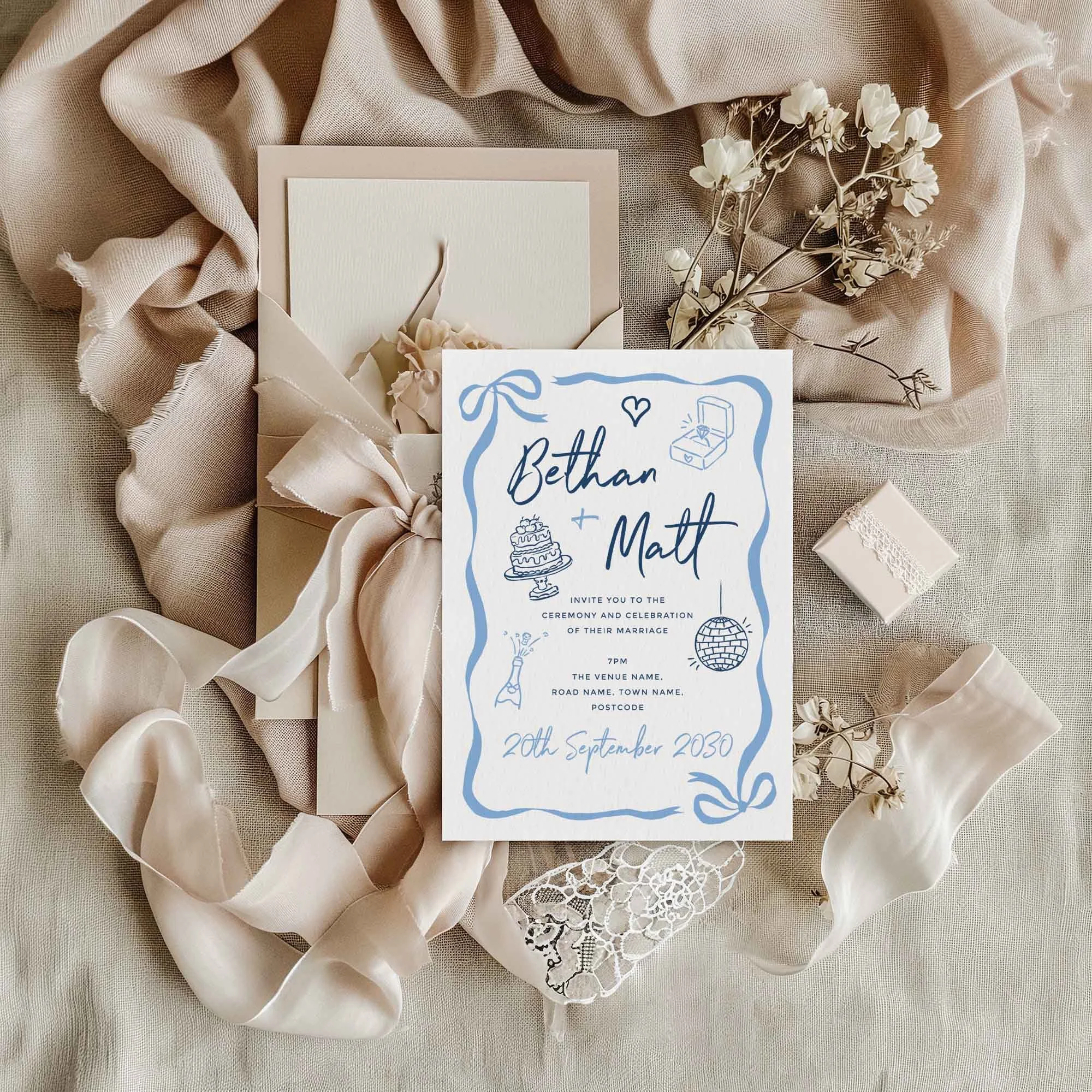 Blue Doodle wedding invitation styled in a flat lay environment with wedding props