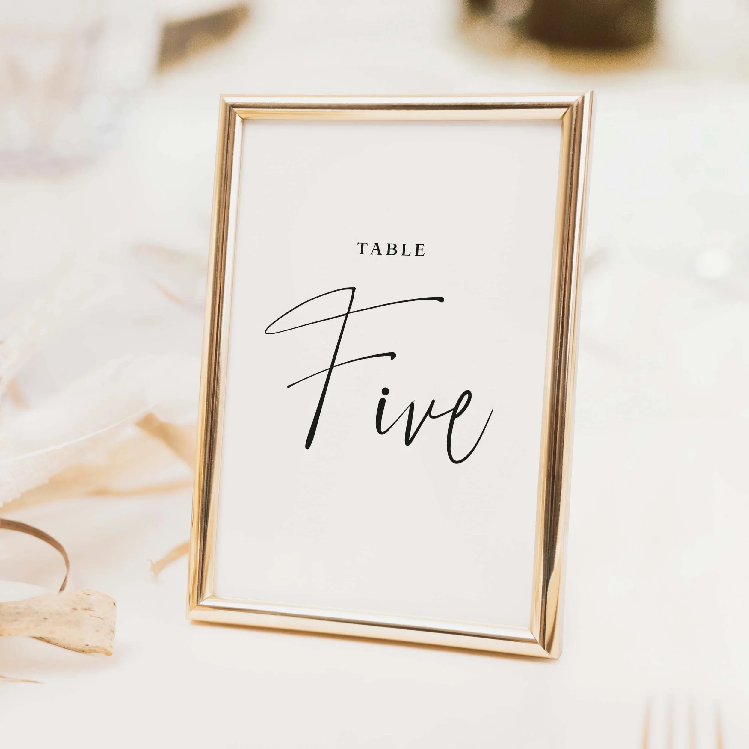 Autograph wedding table number with flowing cursive script typography on clean white background printed on luxury off-white textured card