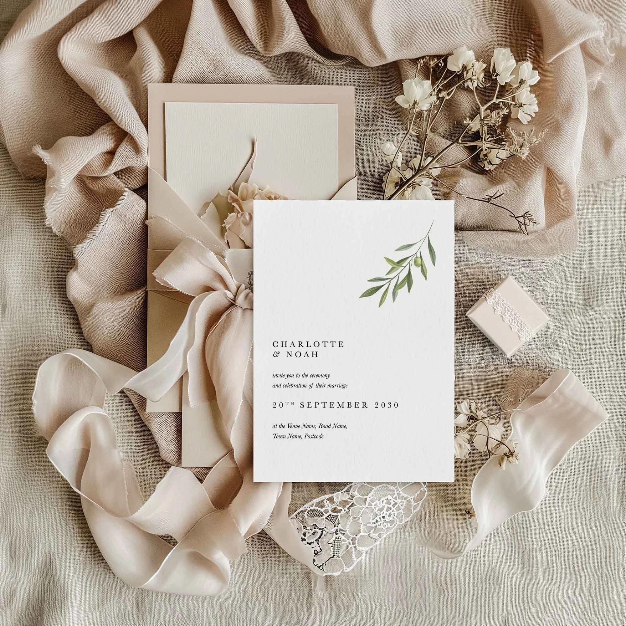 Simple Olive Branch wedding invitation styled in a flat lay environment with wedding props