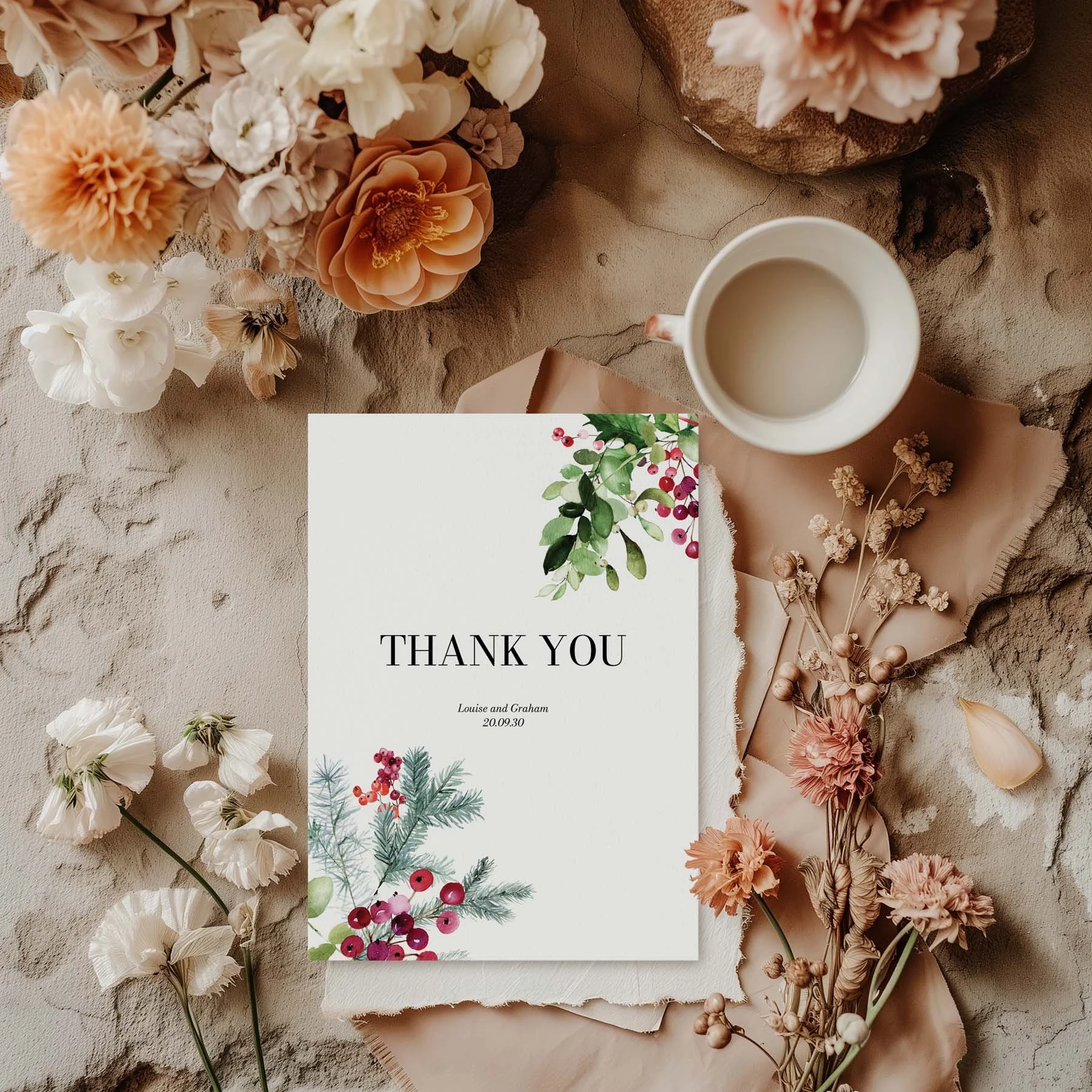 Festive wedding thank you card with a holly, red berry and poinsettia corner arrangement, styled with dried flowers and a white cup on a neutral background