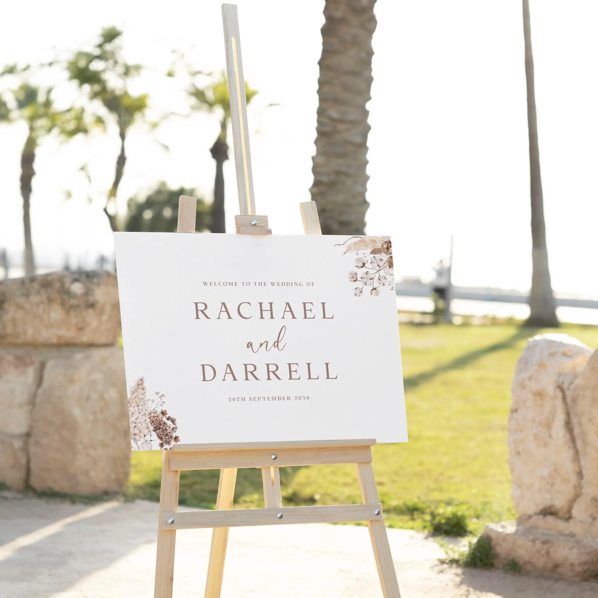 Dried Floral Boho wedding welcome sign displayed outdoors at a wedding venue on an easel