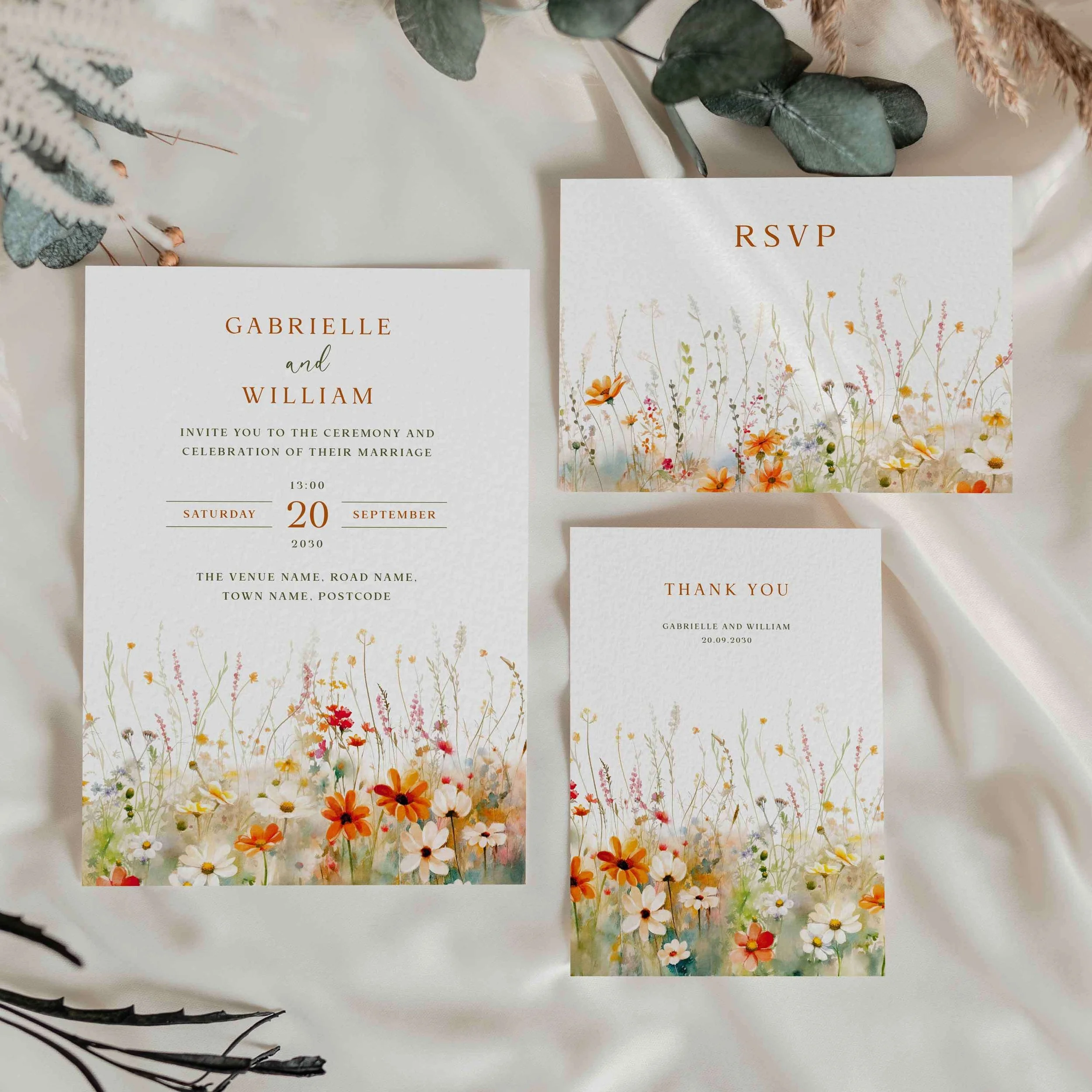 Field Vermilion wedding stationery suite flat lay showing invitations, RSVP cards and coordinating pieces with vibrant orange cosmos and golden wildflower design