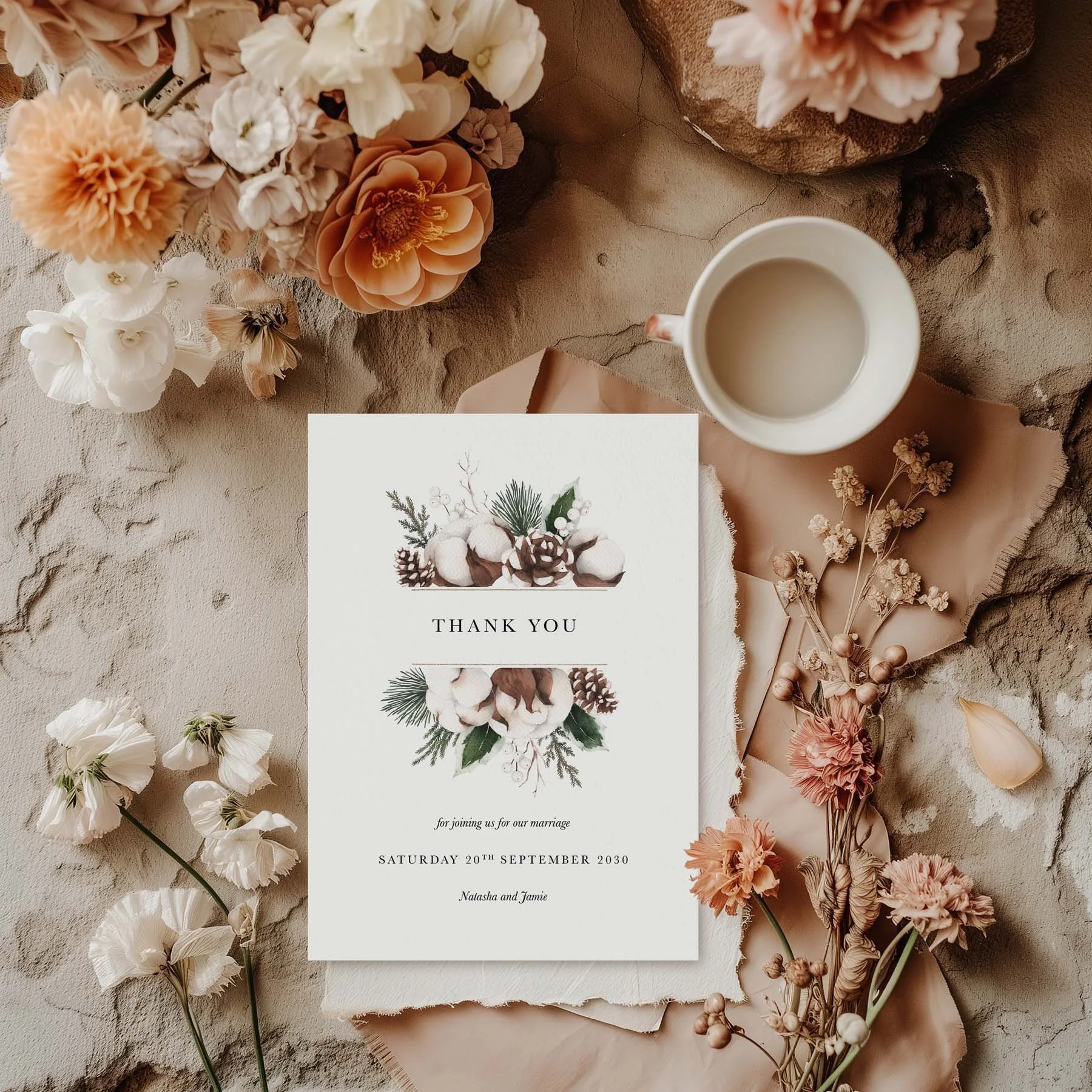 Woodland wedding thank you card with a pine cone and cotton botanical arrangement, styled with dried flowers and a white cup on a neutral background