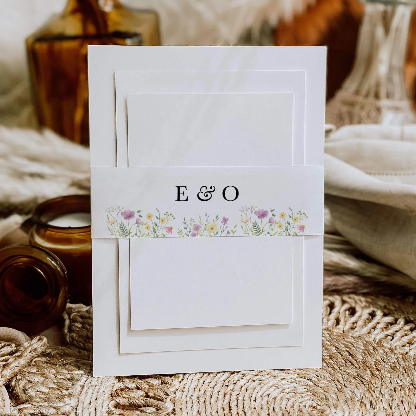 Wildflower personalised wedding belly bands with mixed pink yellow and lilac meadow wildflower illustration and serif initials wrapped around wedding invitations