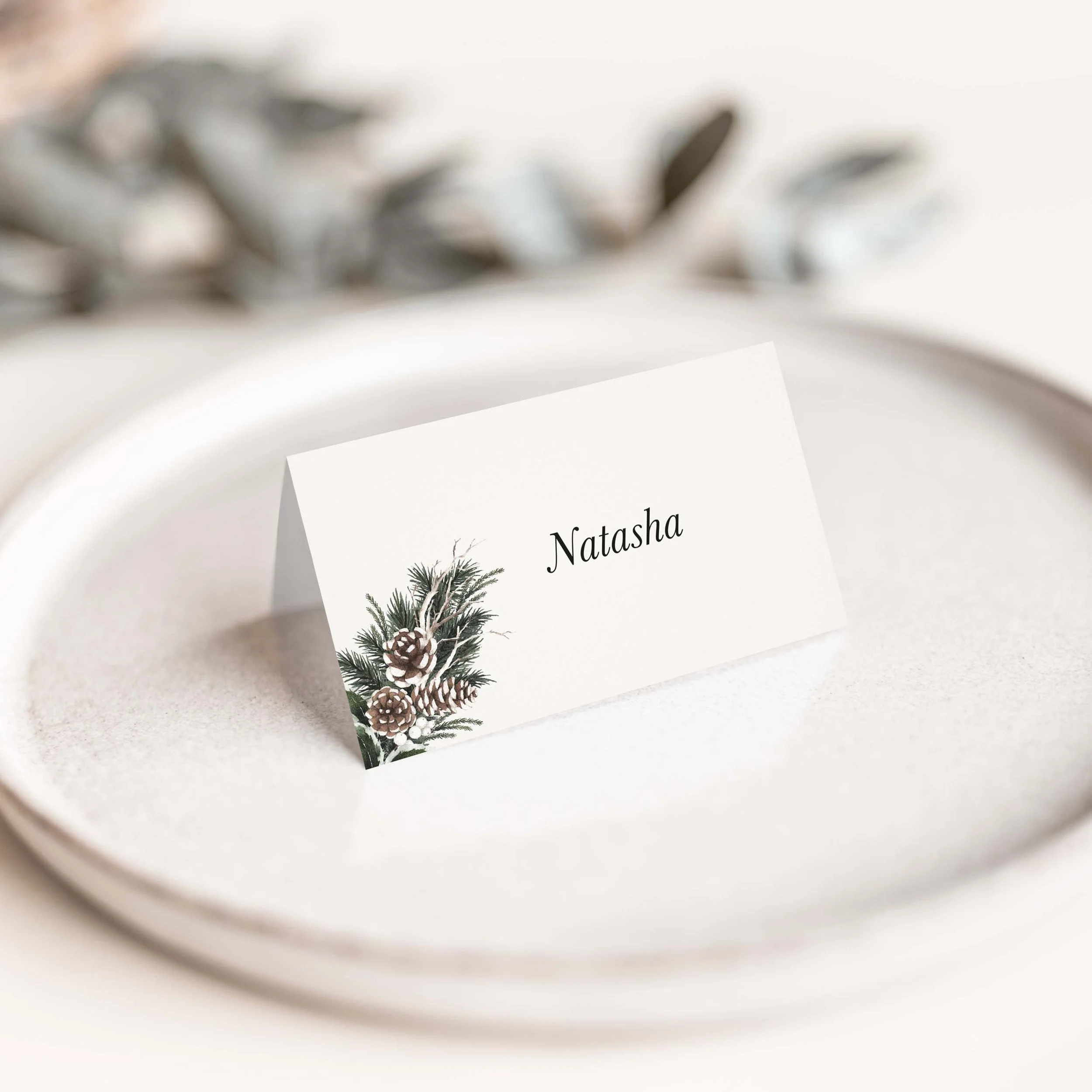 Woodland wedding place card with pine botanical winter foliage illustration and script guest name on luxury off-white card
