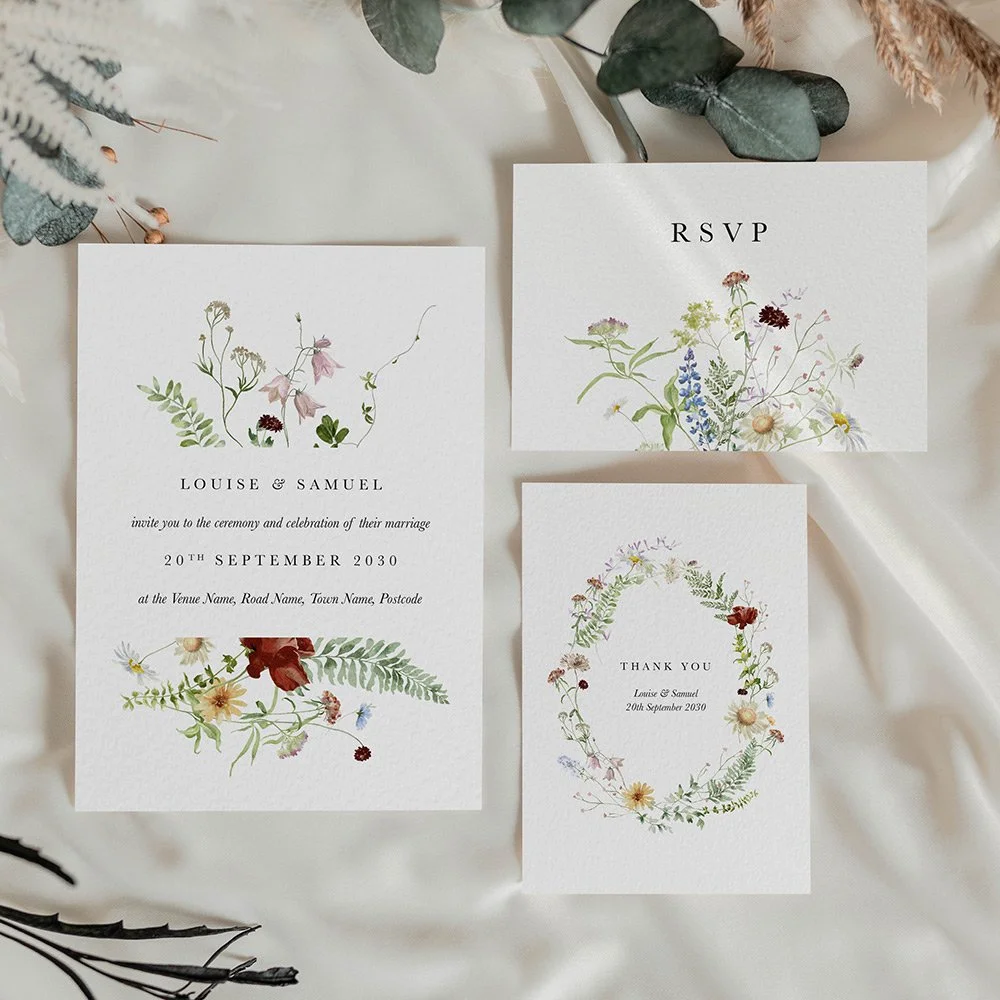 Wedding stationery set including invitation, RSVP, and thank you card, with a blush, peach, and lilac meadow floral frame and elegant serif text.