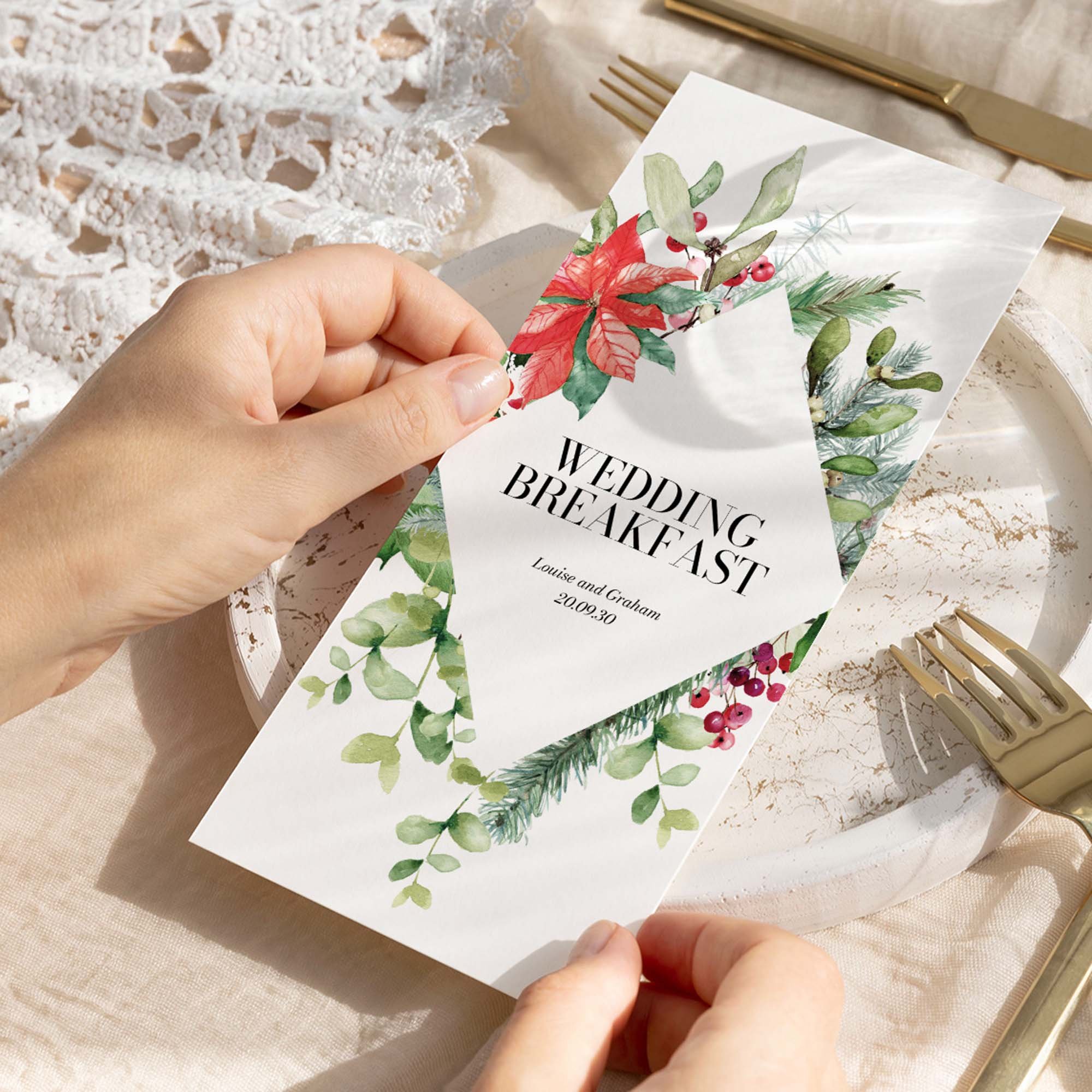 Hand holding a Festive wedding breakfast menu card with a bold holly and red poinsettia illustration in a diamond frame