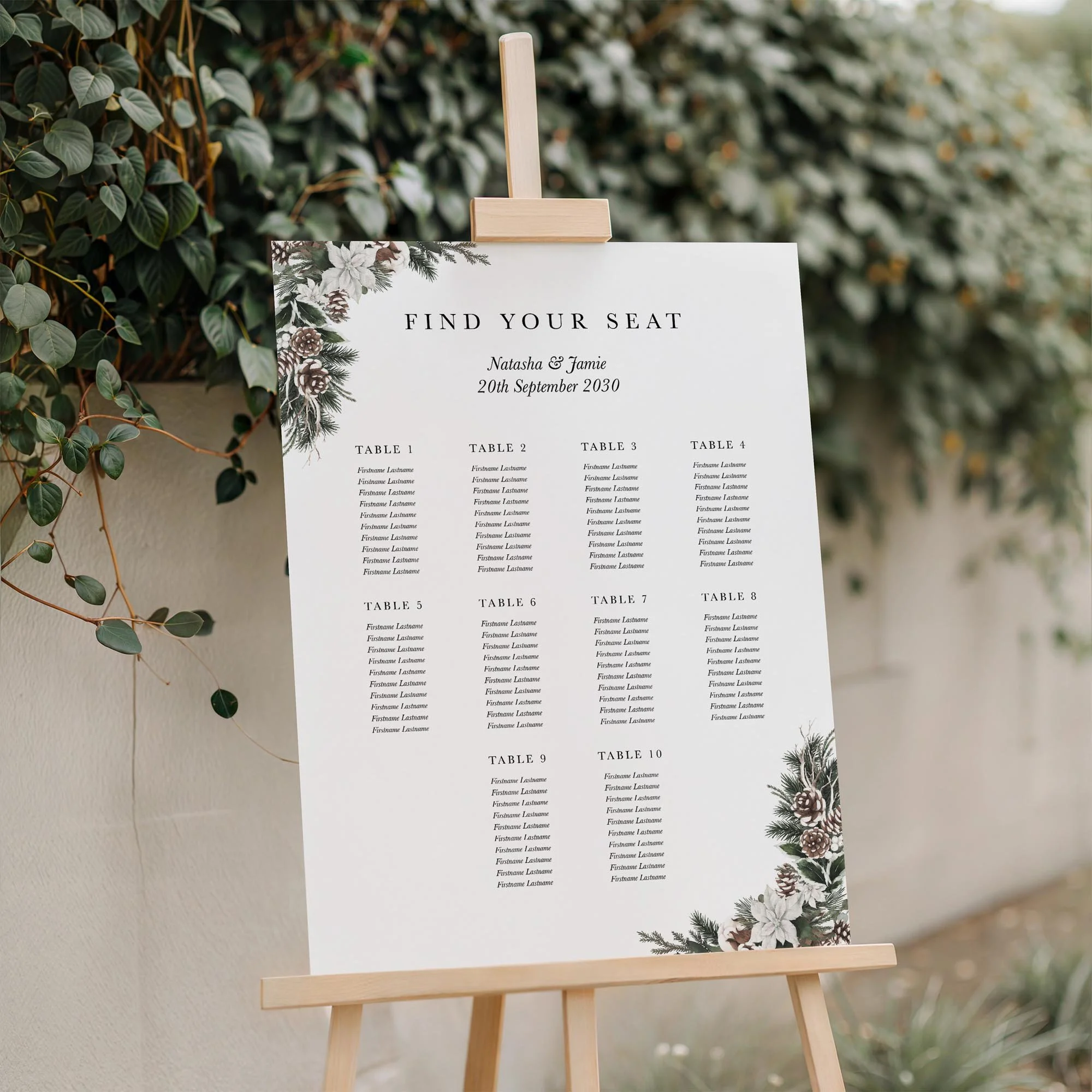 Woodland wedding seating plan displayed on a wooden easel, featuring a pine cone and evergreen botanical design with multiple guest tables