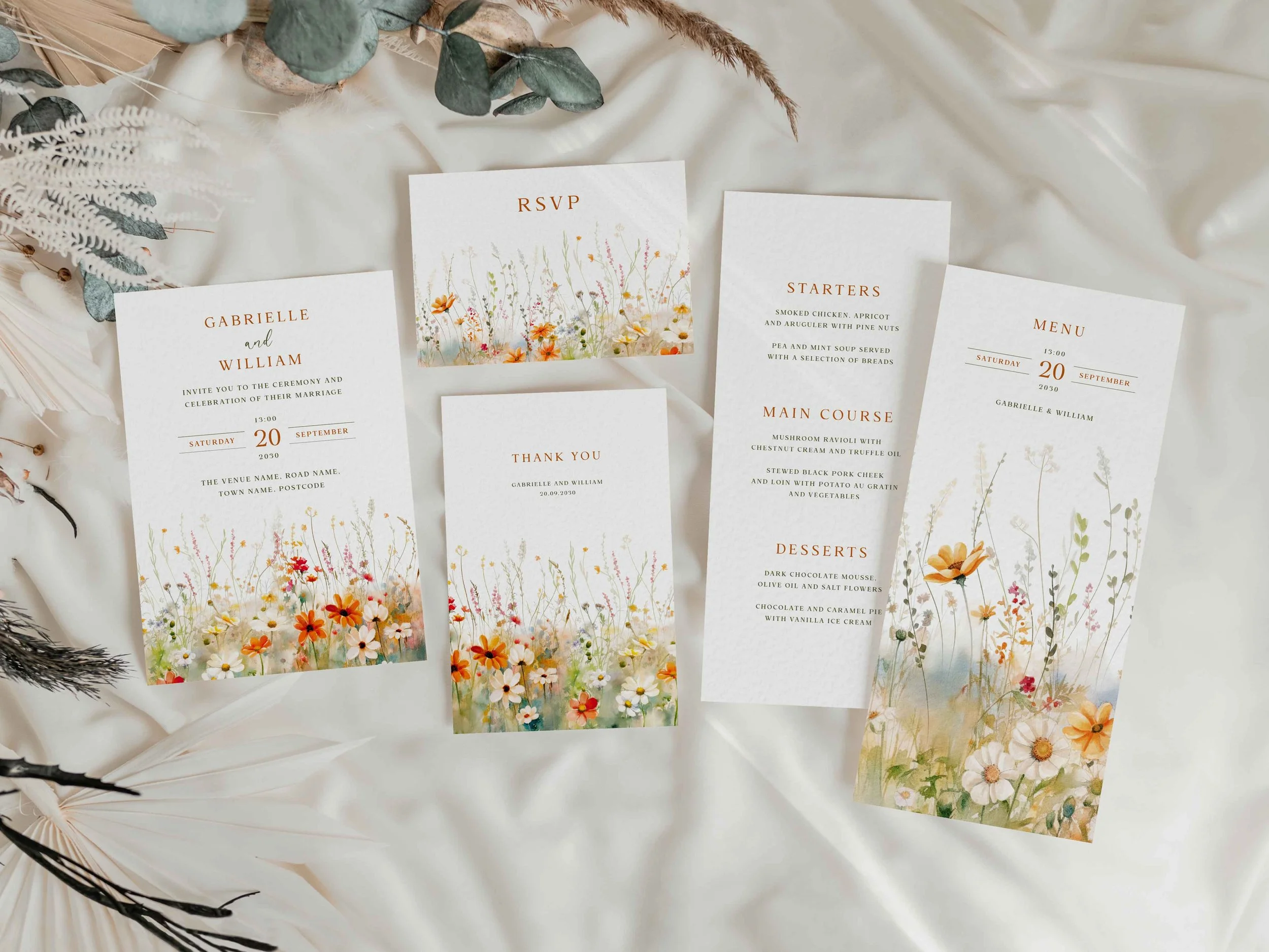 Full Field Vermilion wedding stationery suite flat lay showing invitations, RSVP cards and coordinating pieces with a terracotta and orange wildflower meadow border