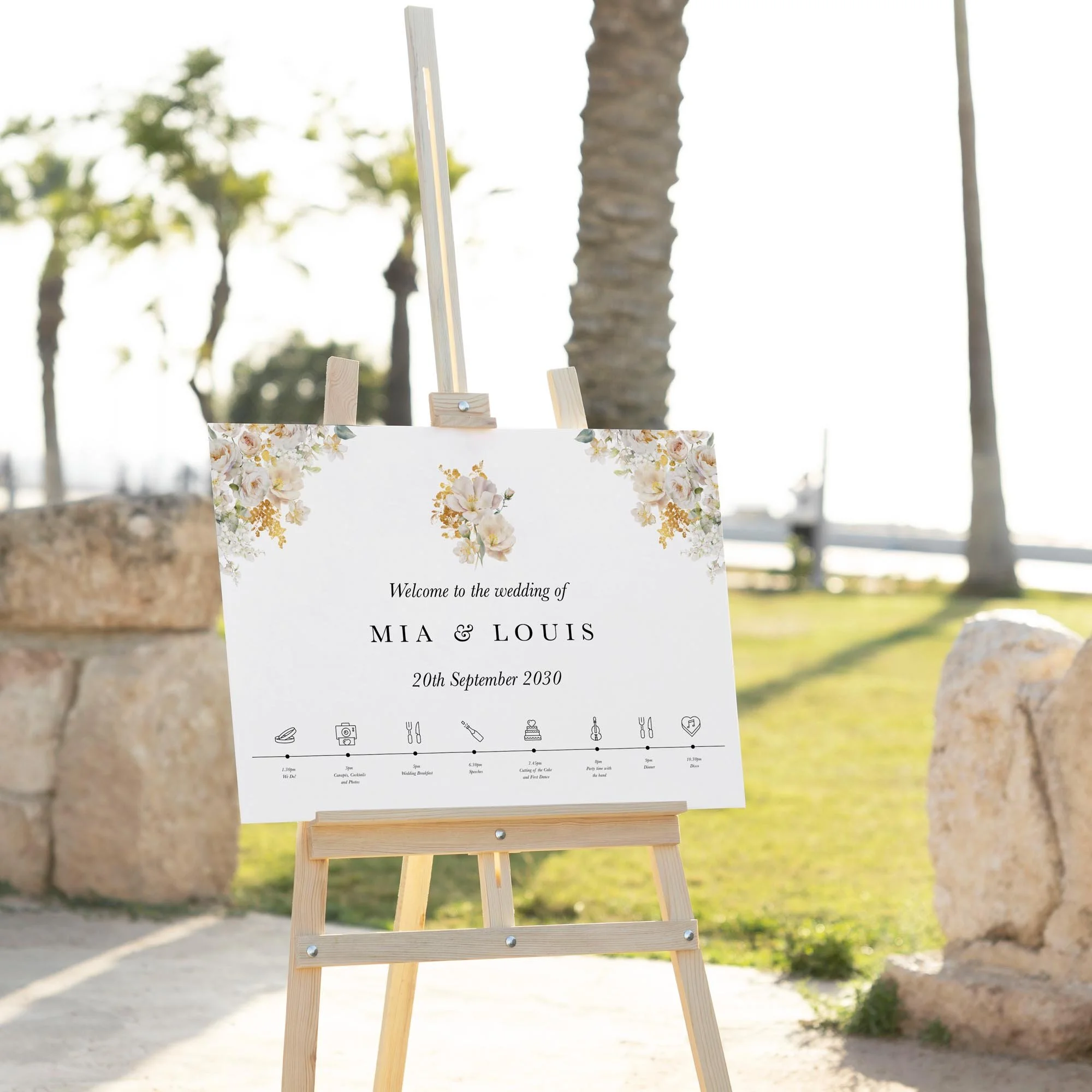 White and Gold Floral wedding welcome sign displayed outdoors at a wedding venue on an easel