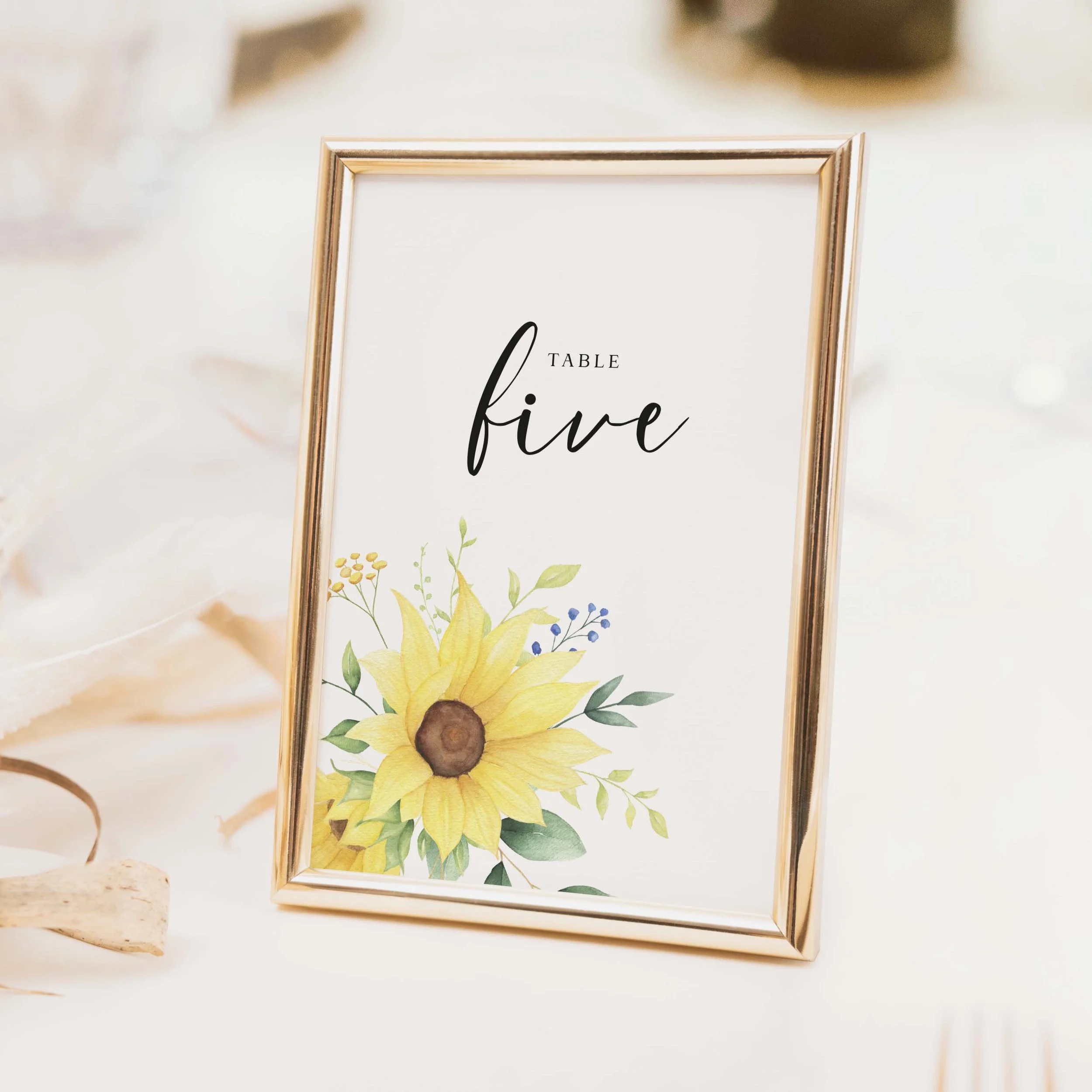 Large sunflower bouquet wedding table number with full floral arrangement and calligraphy script typography on luxury off-white card