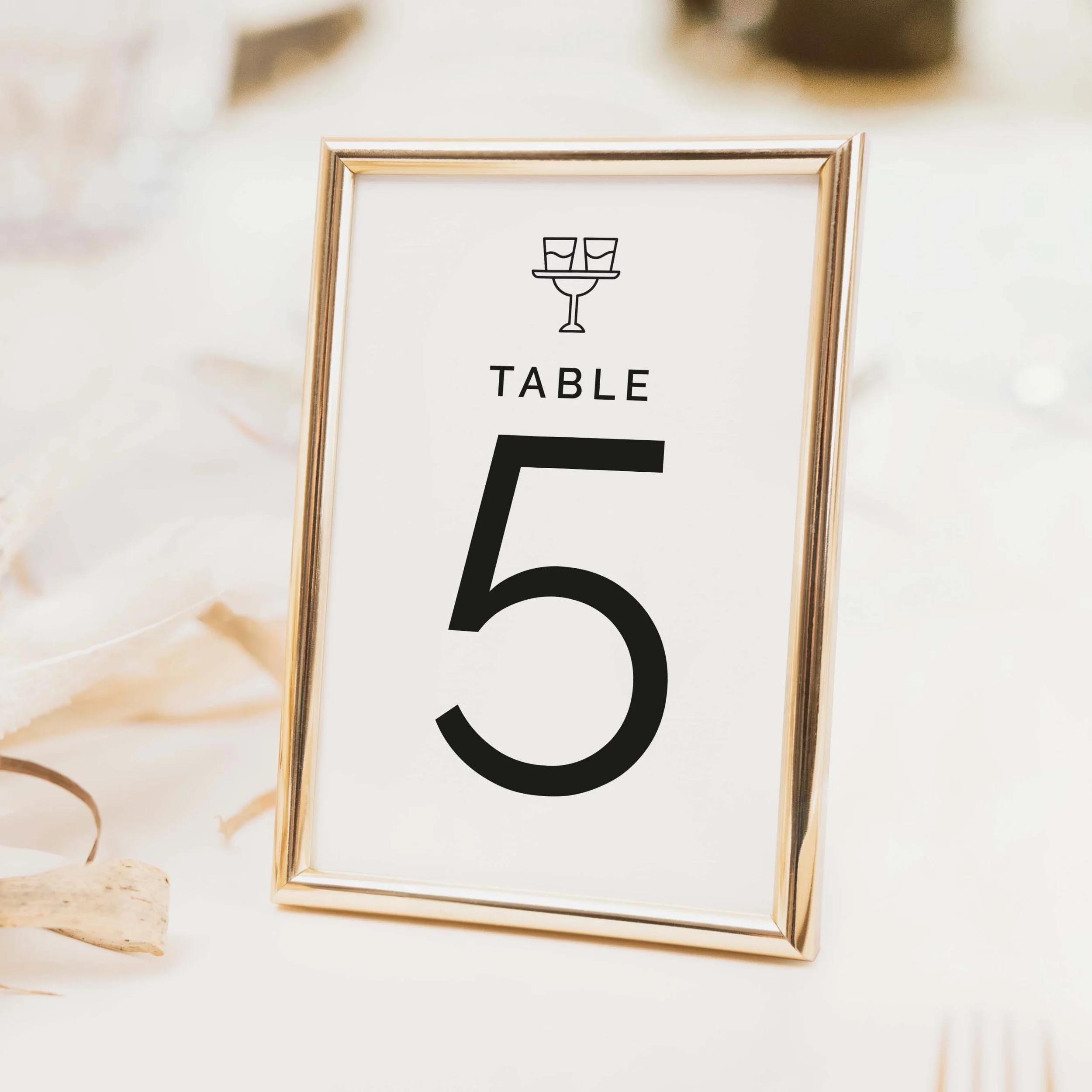 Photograph wedding table number with icon above bold numeral typography on luxury off-white textured card